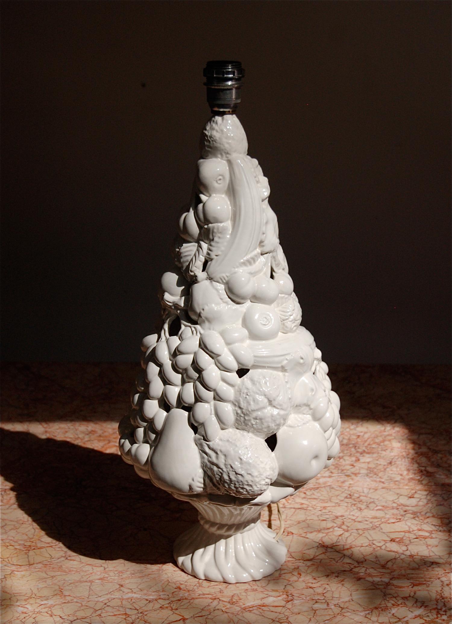 Tall, Italian ceramic table lamp in the shape of a overladen, well stacked fruit basket. A closer look reveals detailed features among the cluster of different fruits (bananas, apples, citrus, grapes, ...). Ceramic base with glossy, white glaze.
