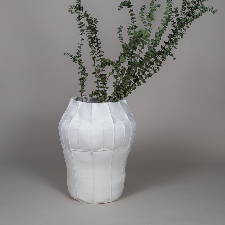 A tall oversized porcelain vessel with leather textured exterior surface and clear glazed interior. As a result of the production process each item is one-of-a-kind. 

A multitude of small leather panels are sewn together to create the leather