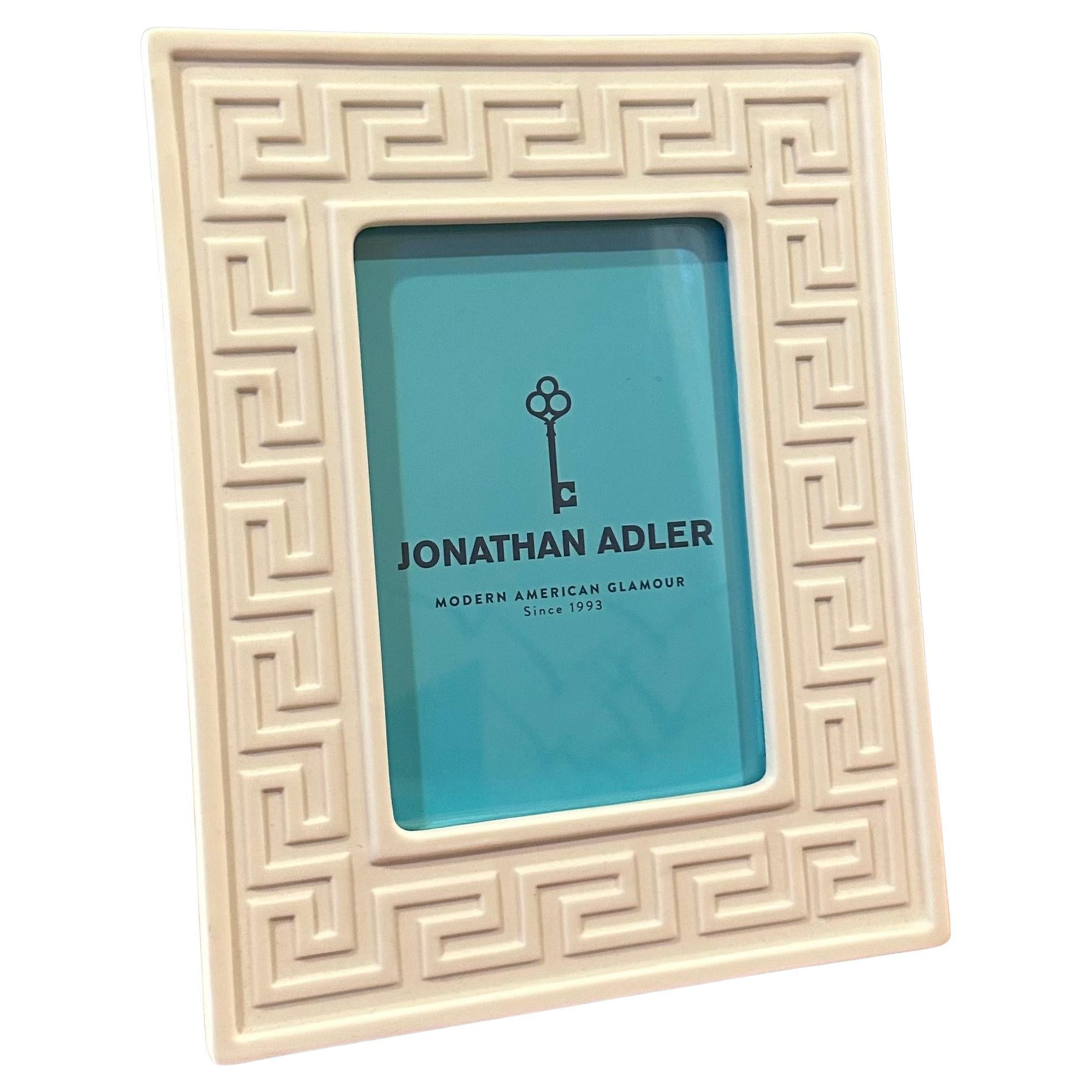 A beautiful white ceramic picture frame with Greek key design by Jonathan Adler, new in original box, circa 2000s.  The frame holds a 4