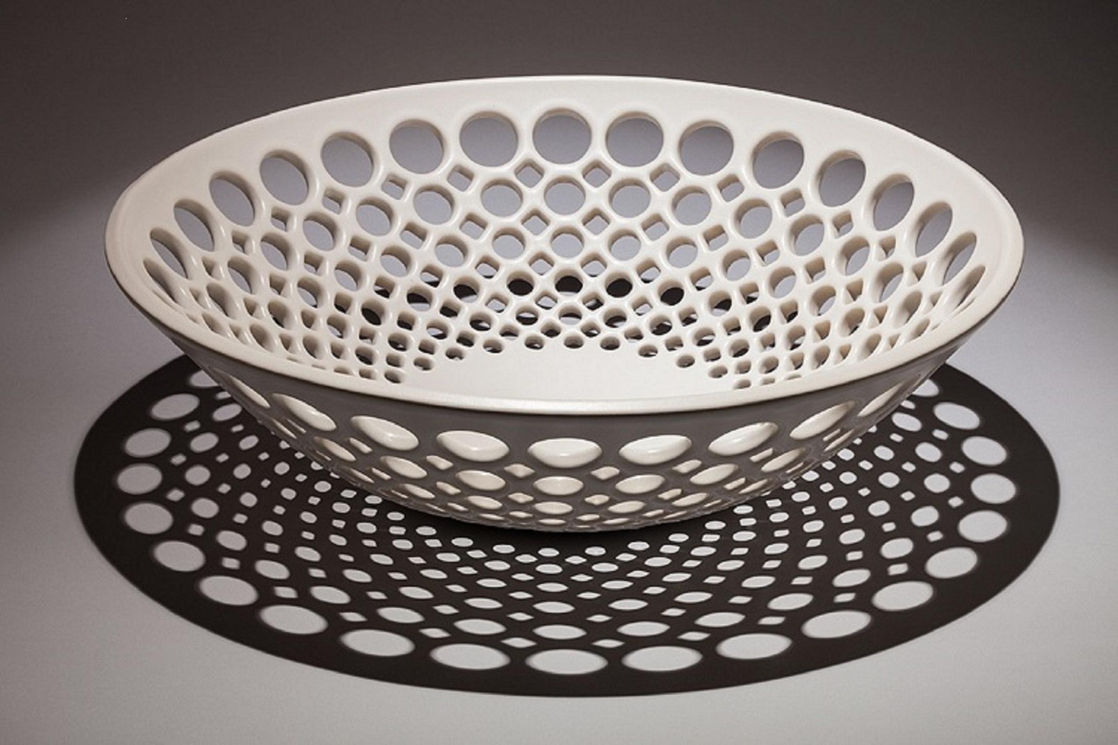 Inspired by Mid-Century Modern design, the bowl is wheel thrown and hand pierced in white stoneware with a white satin glaze. Small holes are created when the clay is still wet and then each hole is painstakingly enlarged and smoothed when the clay
