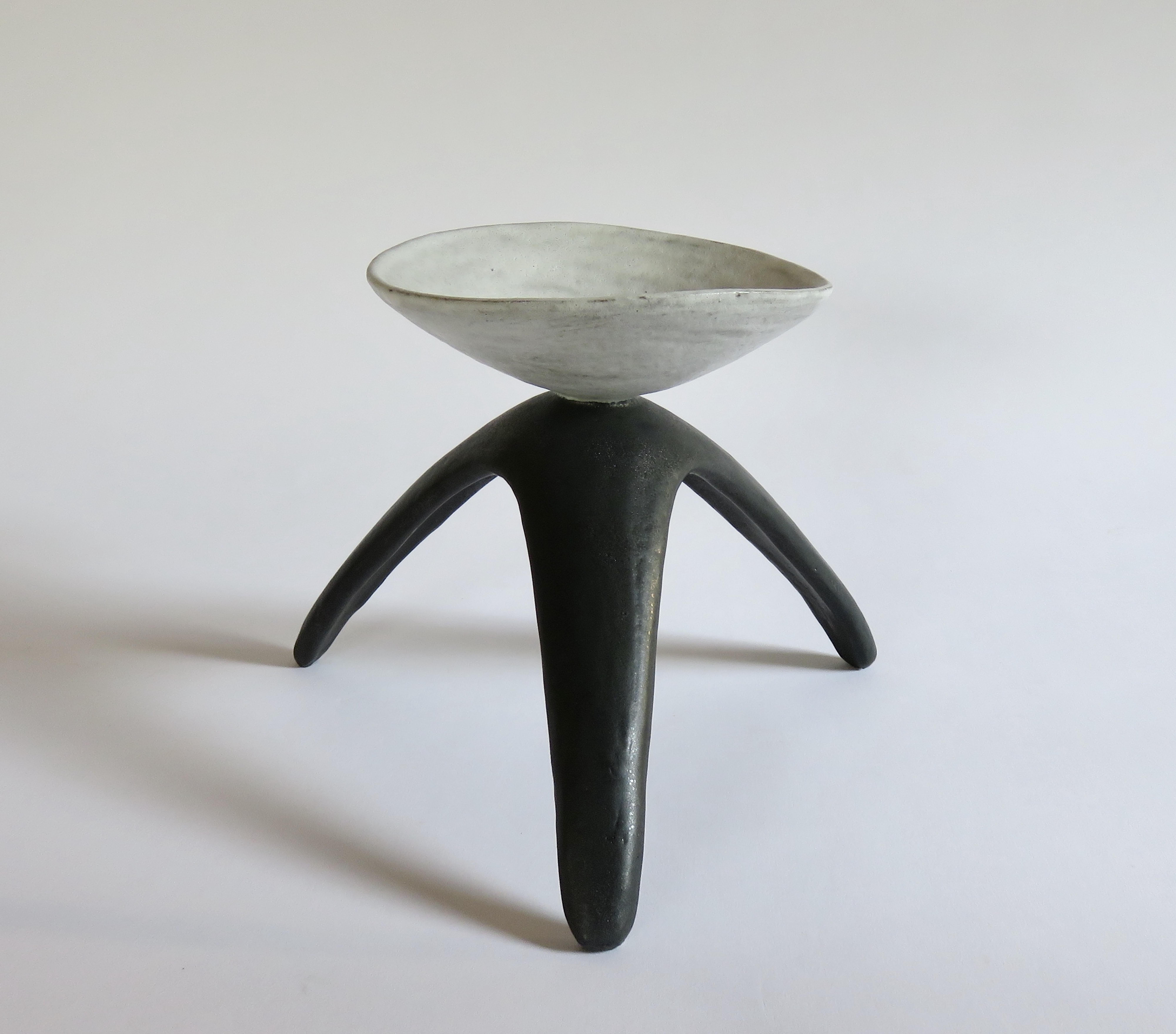 White cup chalice is a modern primitive ceramic piece, designed and hand built by the artist, Helena Starcevic. The cup has a dense white glaze over a dark clay body which adds depth to the glaze. The tripod legs have a matte black glaze with some