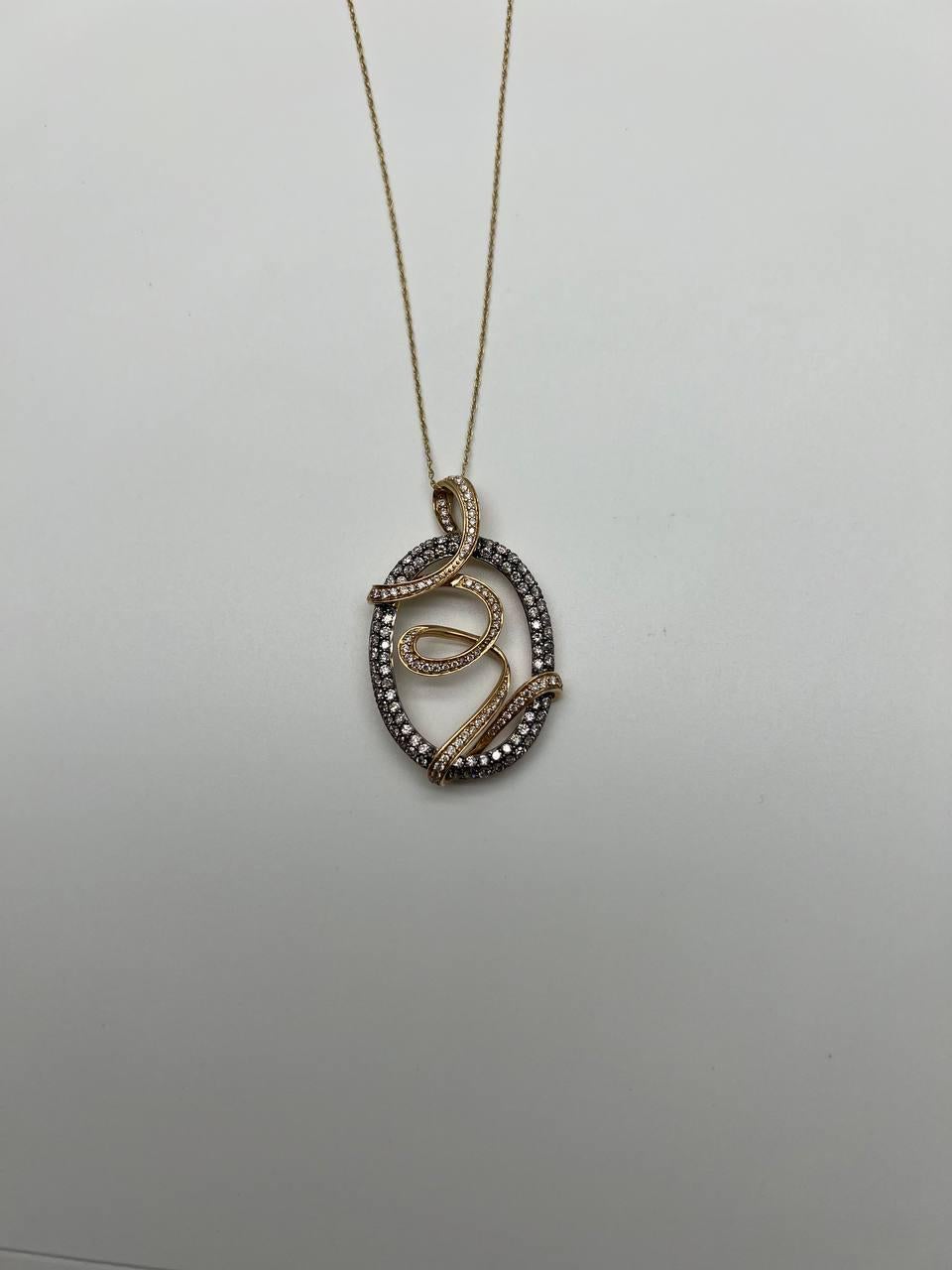 Un'elegante collana con un pendente dalle curve intricate e diamanti scintillanti di diversi colori, incastonati in un delicato design in oro massiccio 14k. Il ciondolo è di forma ovale con un motivo a vortice, ornato da scintillanti accenti di