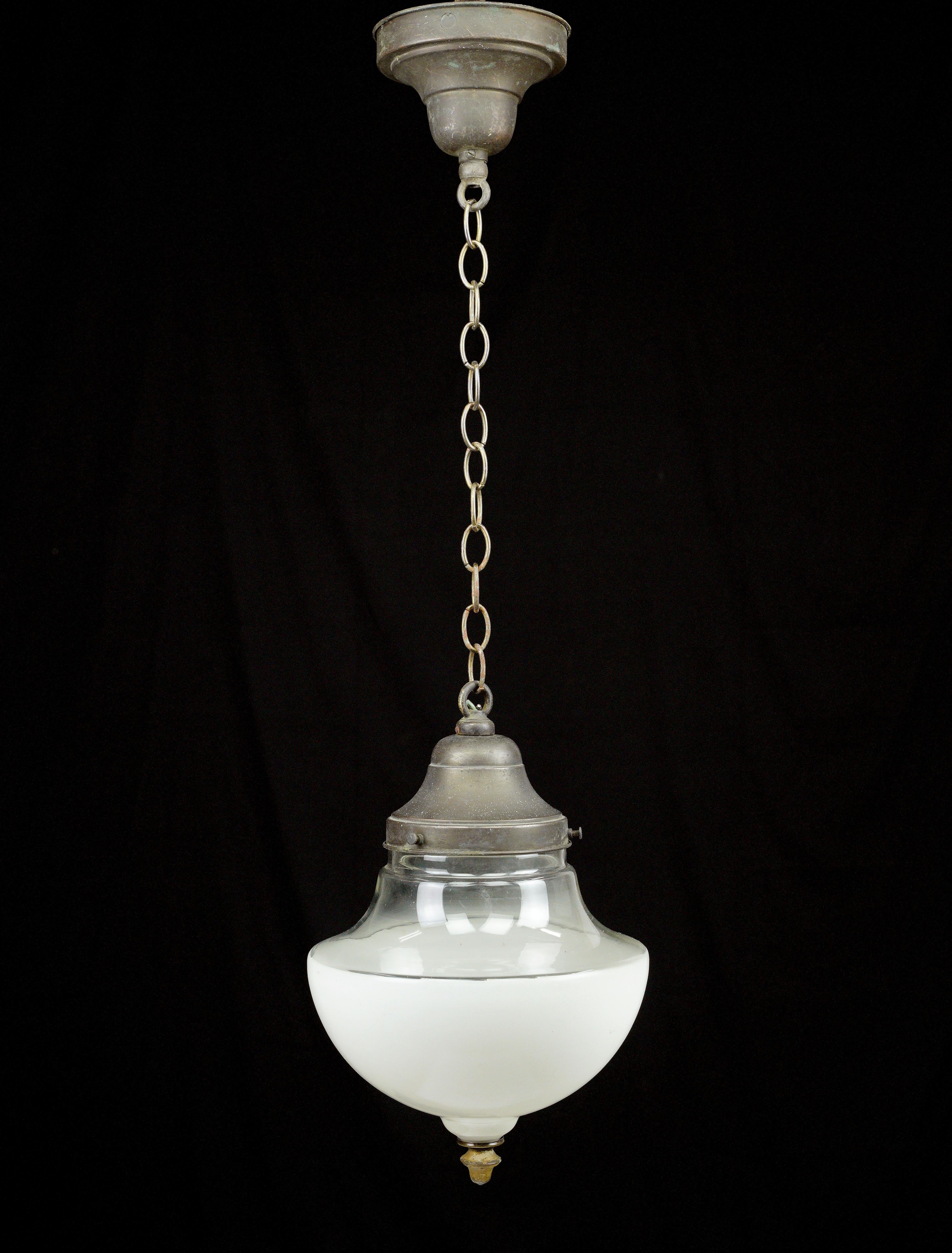 This antique pendant light exudes elegance. With a white and clear mushroom glass globe and a brass finished steel chain, it captures the charm of a bygone era. This pendant light adds a touch of classic sophistication, combining timeless design