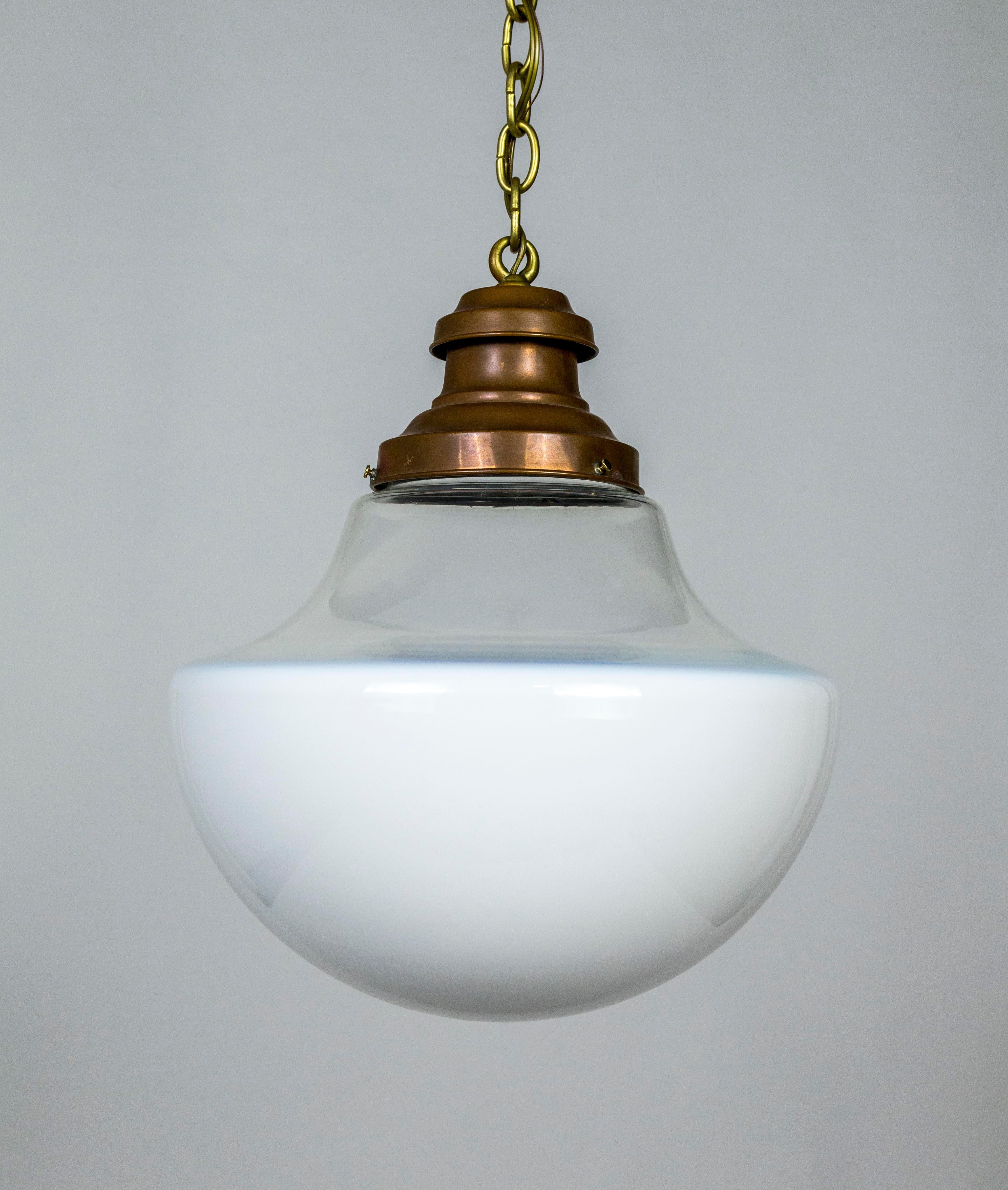 A pendant light with antique, two-toned, blown glass in a swooping shape; white on the bowl and clear on top. Held with a copper finished shade holder, and a long, gold chain. Newly wired. 58