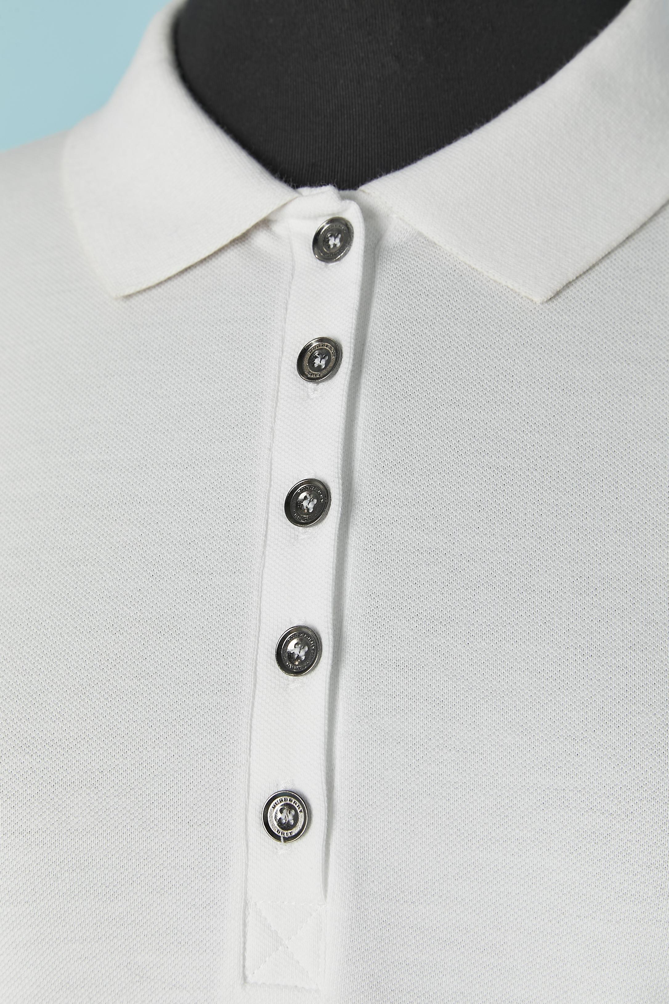 Polo de algodón blanco . Composición del tejido: 98% algodón, 2% elastán. Comprueba el patrón bajo el cuello y en el interior del borde de la manga. Botón de Brande y cierre de ojal en la parte media superior delantera + un botón extra