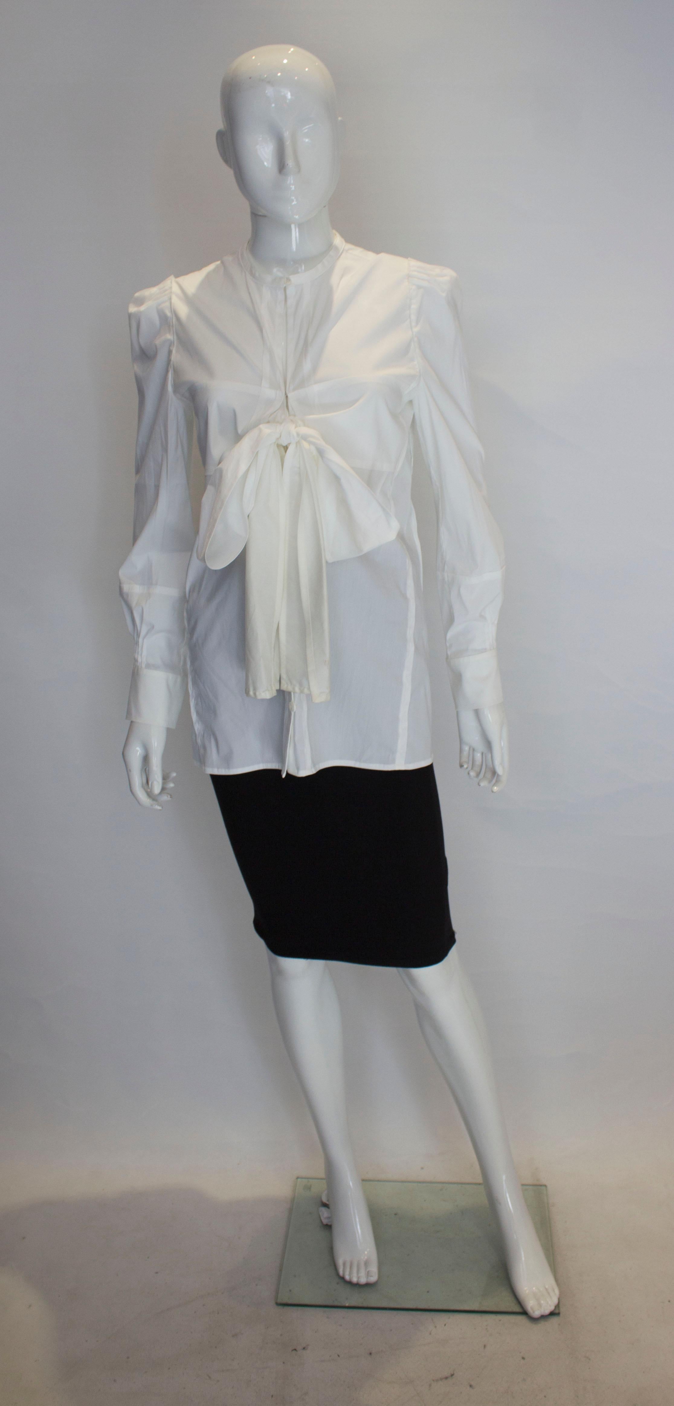 A chic shirt by Yves Saint Laurent Rive Gauche line. The shirt has attractive detail on the shoulder and cuffs. It is collarless with a v neckline, front button opening and tie detail.