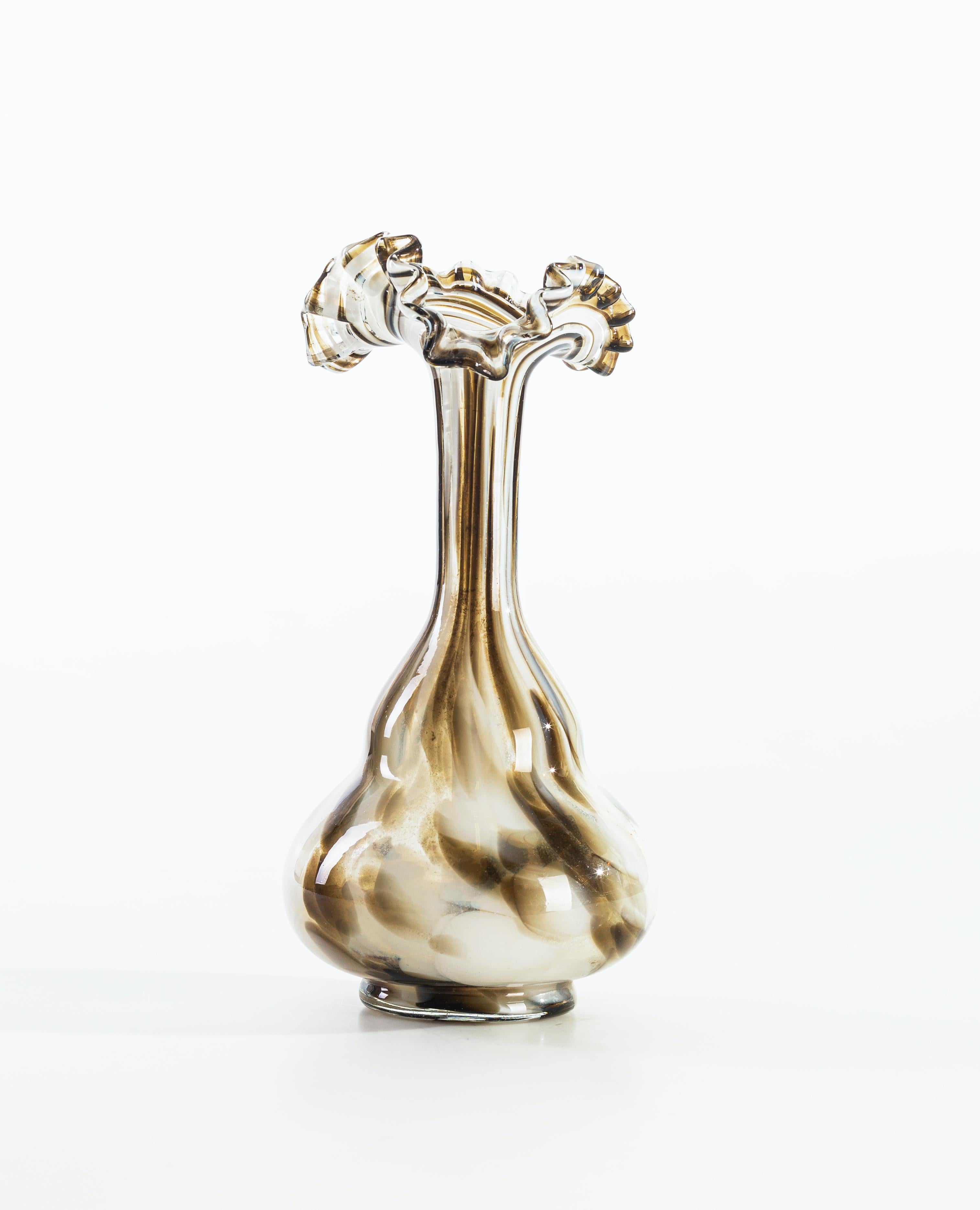 This white, cream and caramel glass vase, made in Austria in the 1960s, is exemplary for the beauty of its shape: a double-bulb body, with a tall and slender flared neck above with a shape remembering a flower. The upper mouth has a wavy edge. The