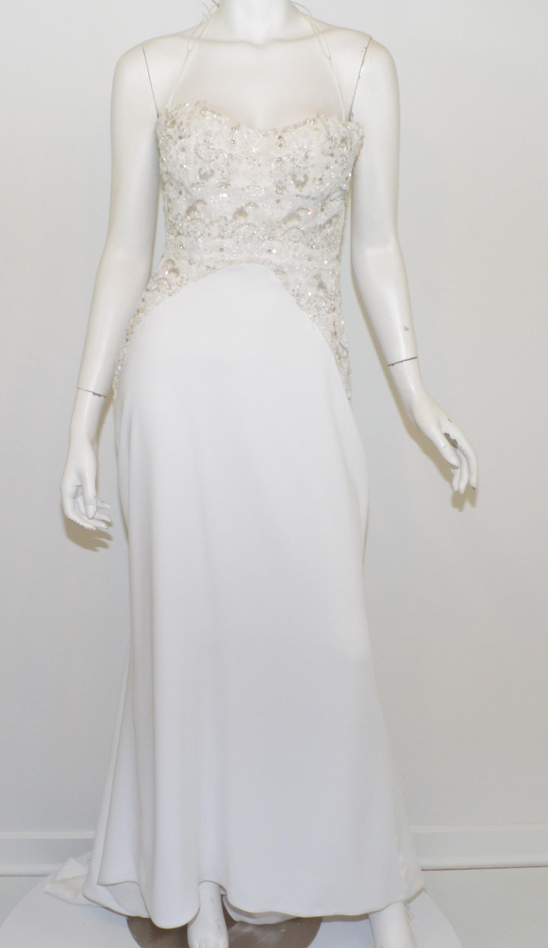 White “Nikki” wedding dress features an assortment of bead, Sequin, and rhinestone embellishments along the bodice atop of a mesh layer with a back zipper fastening (decorative buttons along the zipper). Dress has a boned bust/bodice and is in great