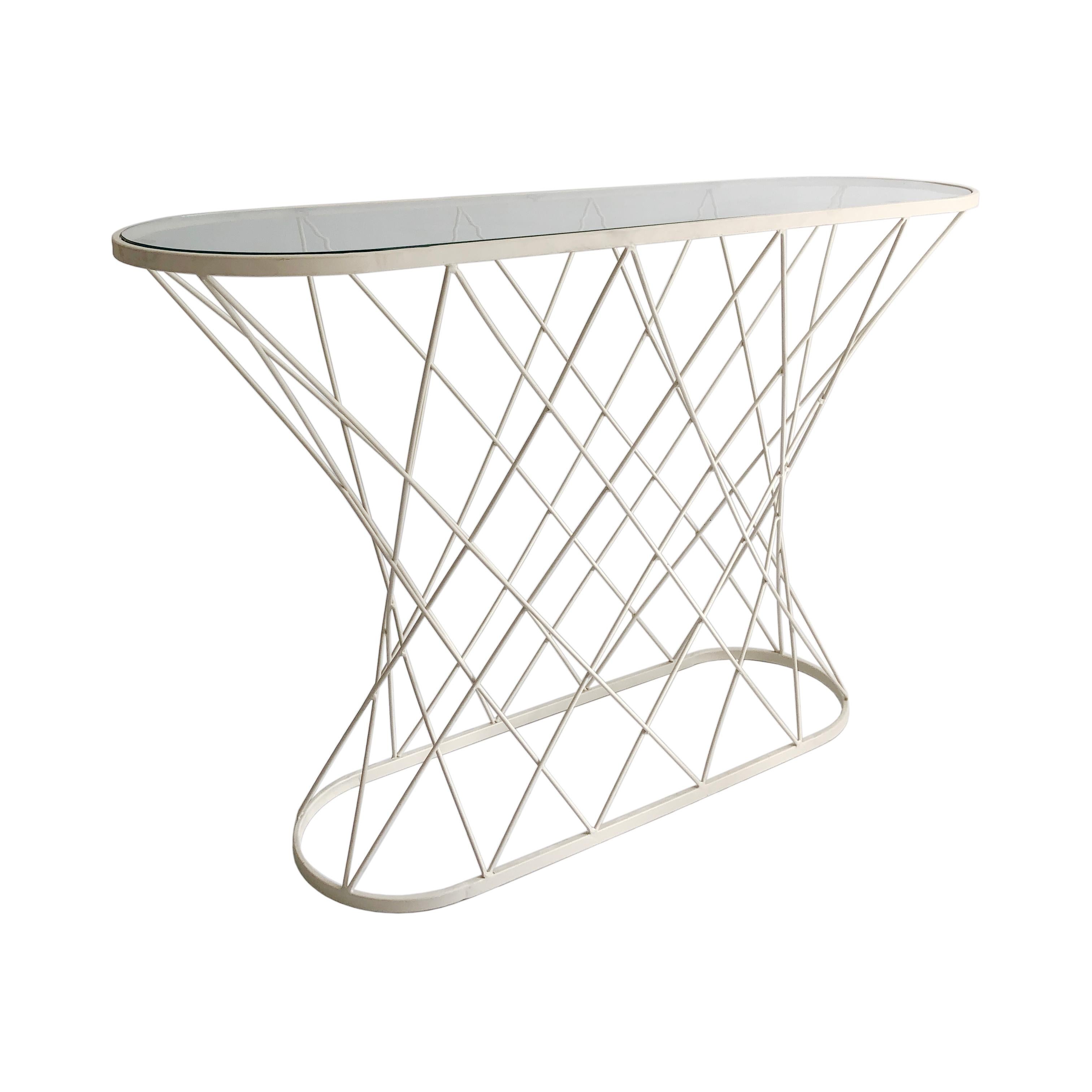 The playful twisted geometric pattern created by this console table gives a superb latticework effect. A white powder-coated metal oval serves as the base for numerous metal poles, crossing on the diagonals and leading to an oval shaped clear glass