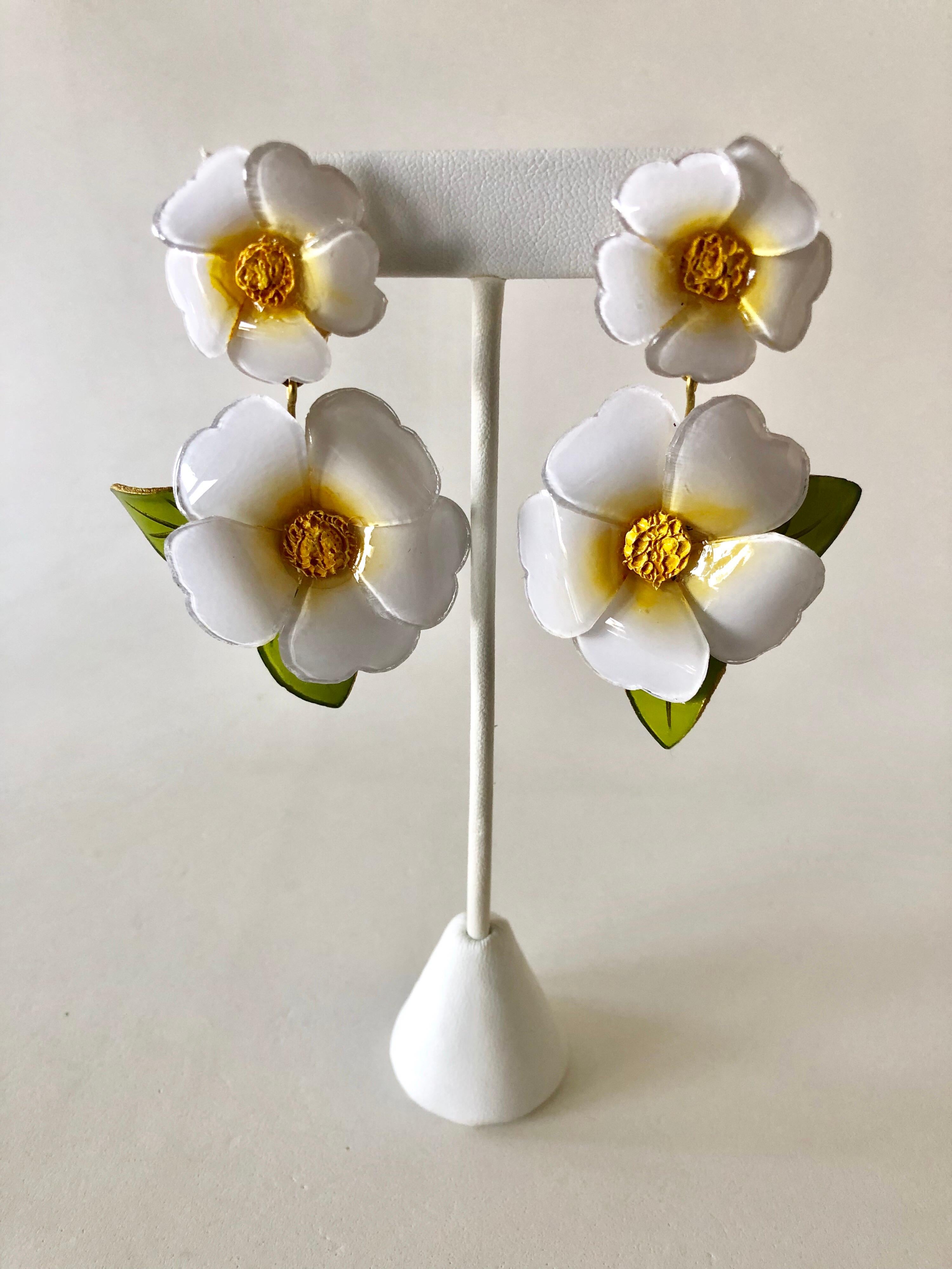 Light and easy to wear, these contemporary handmade artisanal clip-on statement earrings were made in Paris by Cilea. The lightweight earrings feature two large a enameline (enamel and resin composite) white daisy flowers. The flowers are oversized