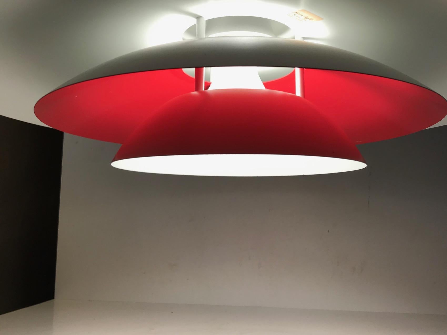 Large tiered pendant/hanging light in white powder-coated steel. Interior shading with red reflector that creates cosy and warm light. Designed and manufactured by Lyskær in Denmark during the late 1970s in a style reminiscent of Louis Poulsen's PH4