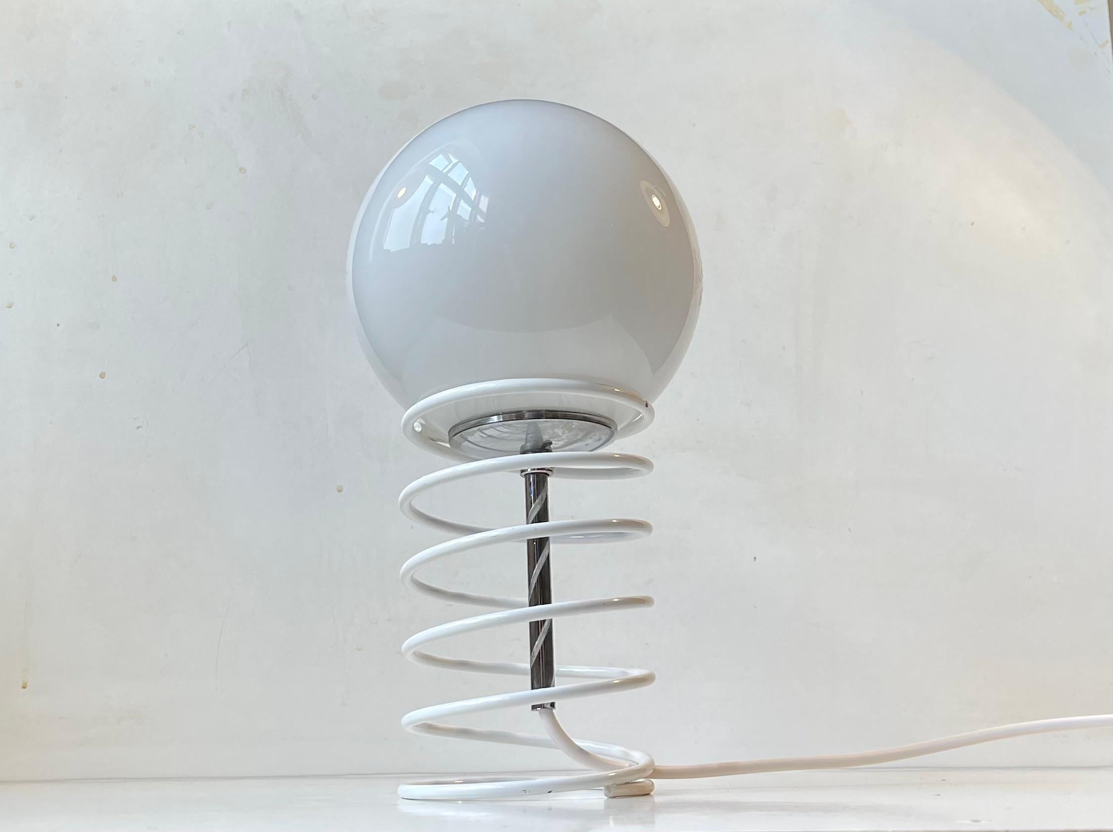 Une petite lampe de table simple composée d'un ressort en acier laqué blanc retenant librement une sphère en verre opalin dans un cadre chromé. Il a été fabriqué par Bell au Danemark vers 1980-90. Son style rappelle celui de Verner Panton et de Fase