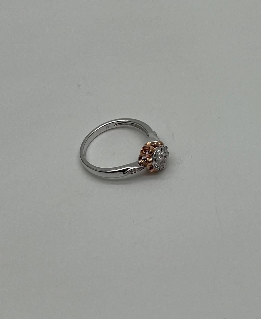 A harmonious blend of elegance and contrast.
This striking ring features a central diamond cluster, encircled by a delicate gold petal design. The intricate detailing extends to the band, adorned with subtle diamond accents on each side, enhancing