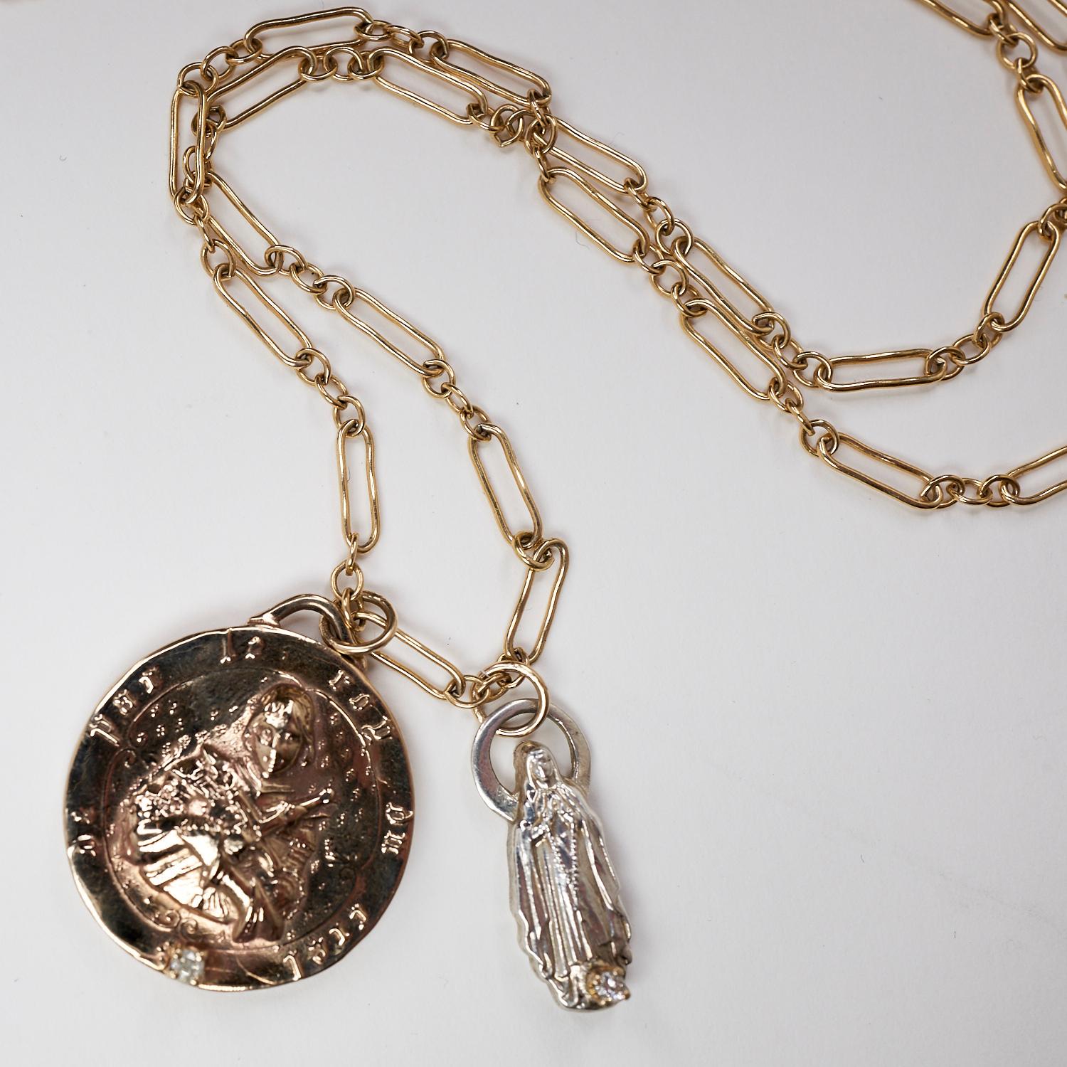 Deux diamants blancs sertis dans une griffe en or sur un pendentif médaille pièce de monnaie Jeanne d'Arc en bronze et une figurine de la Vierge Marie en argent, le tout suspendu à une longue chaîne de 24 pouces,  Unique en son genre, les pendentifs