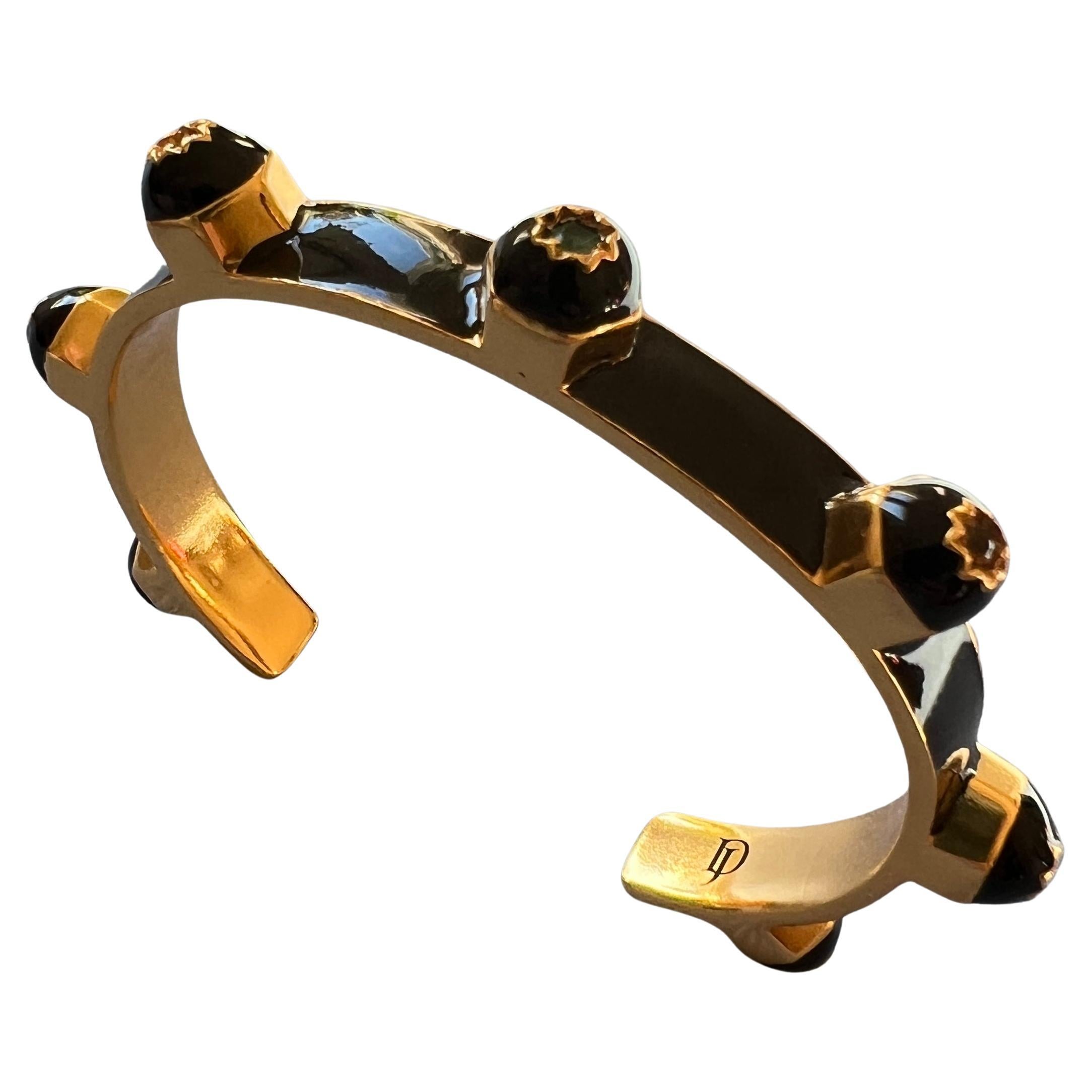 This black enamel chakra cuff bracelet by J Dauphin features seven natural gemstones set in engraved eight-pointed stars, aligned in chakra order and crafted in 14k gold-plated brass. With its bold studded profile and Victorian inspiration, the