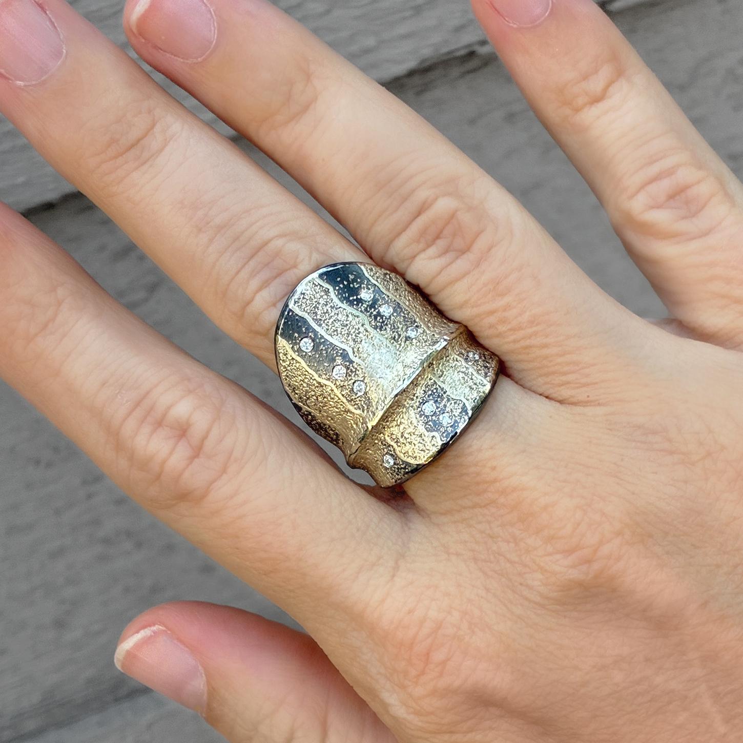 Un'audace dichiarazione di arte moderna: questo anello Atelier Zobel, realizzato a mano, abbina il ricco oro giallo 24 carati all'argento sterling ossidato in un sorprendente design a scudo ripiegato. Incastonata a filo con 0,10 carati di diamanti