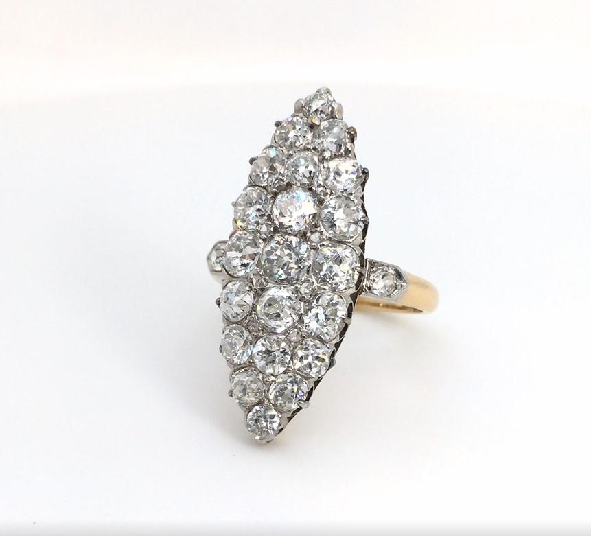 This enchanting vintage-style ring demands a closer look. Its marquise shape mount elongates the ringer of its wearer, while its cluster of white round brilliant diamonds, set in a navette style, shimmer as they catch the light. The look is