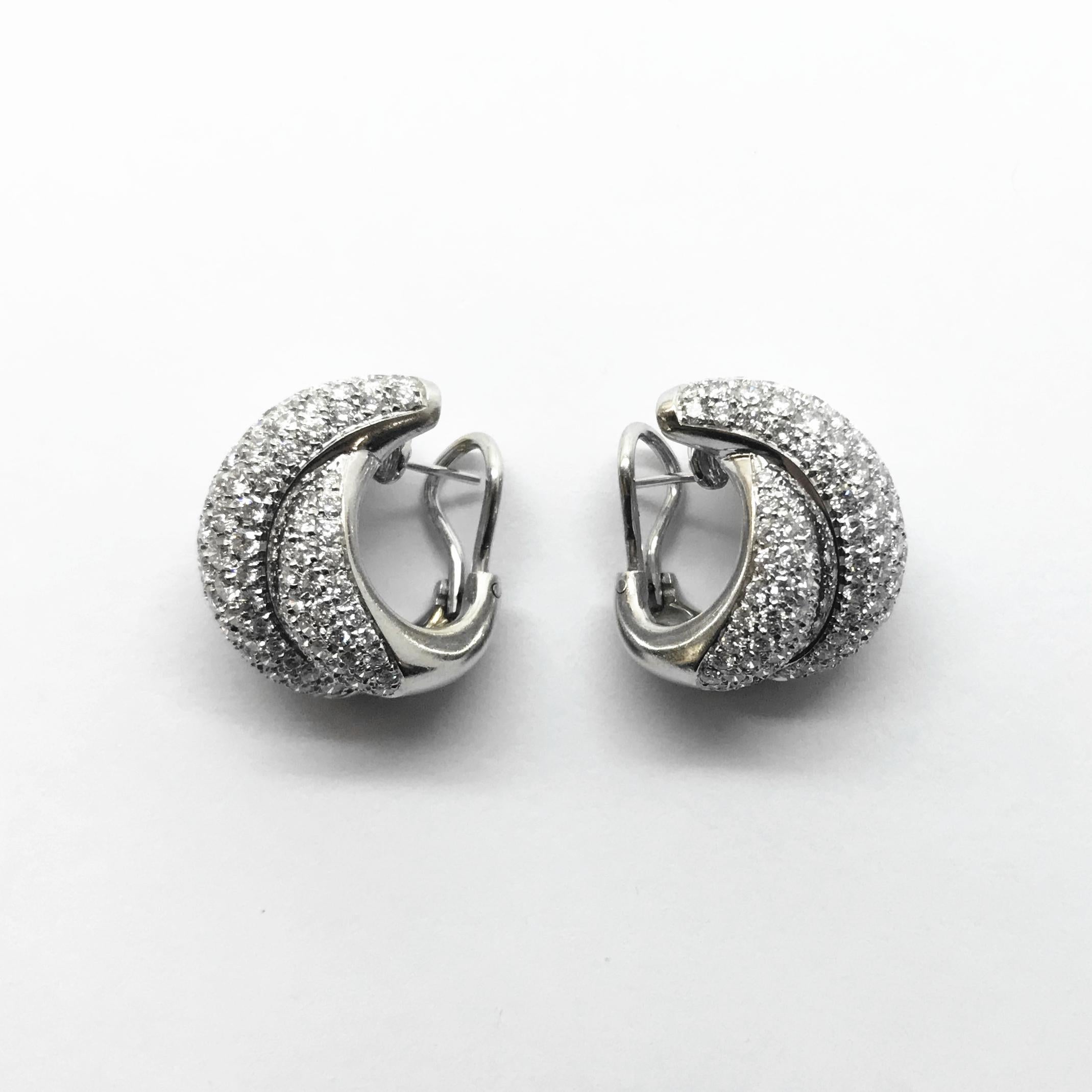Damiani 18K white gold and diamond pavé hoop earrings with post and clips. The “Gomitolo” collection of a three sectional crossover style is set with graduated sized round brilliant cut diamonds totaling 5.59 cts and estimated to be F-G color and VS