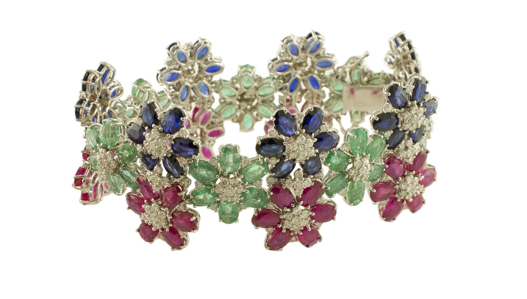 Elegant flower theme link bracelet in 14k white gold composed by rubies, emeralds and blue sapphires petals and little shining white diamonds in the center
Diamonds 8.46 ct 
Rubies, Emeralds, Blue Sapphires 72.71 ct 
Total Weight 50.60 g 
R.F +