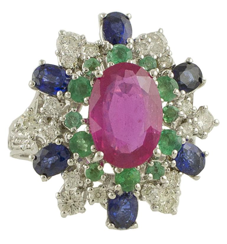 Amazing Cocktail ring in 14K white gold mounted with gorgeous big ruby in the center surrounded by little emeralds crown and embellished by shining white diamonds  and deep color blue sapphires
Diamonds 0.86 ct 
Emeralds, Ruby and Blue Sapphires