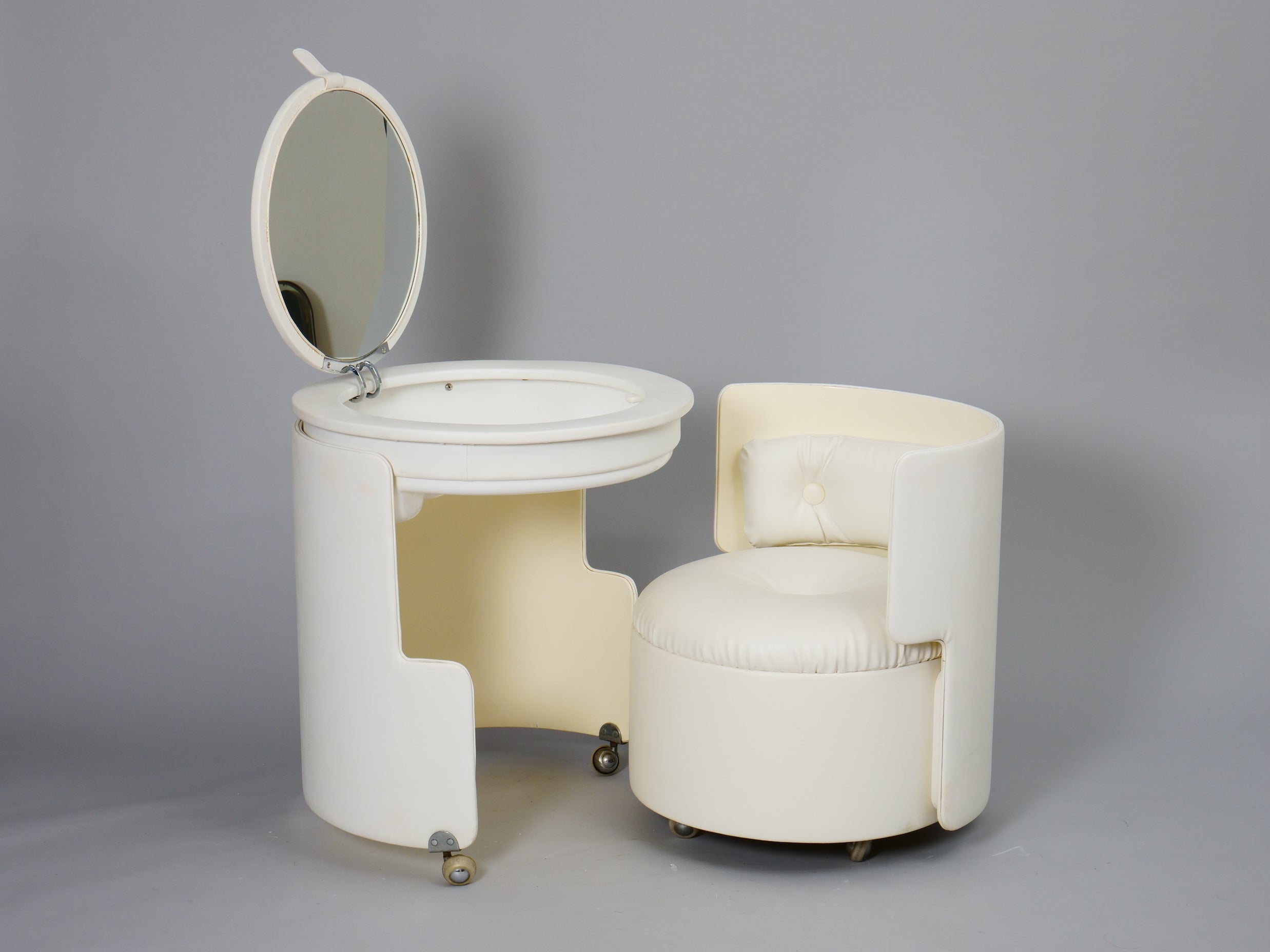 Vanity table model 'Dilly Dally' designed by Luigi Massoni for Poltrona Frau Italy c1960.

This model comes with the original mirror and light. 

Comprises a chair on castors which fits into the table to form a round cylinder. The table opens to