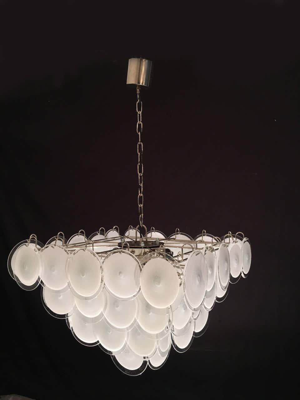 Each chandelier is made of 50 white discs of precious Murano glass and arranged on four levels.
 Five light bulbs E 14.
 Available also a pair.