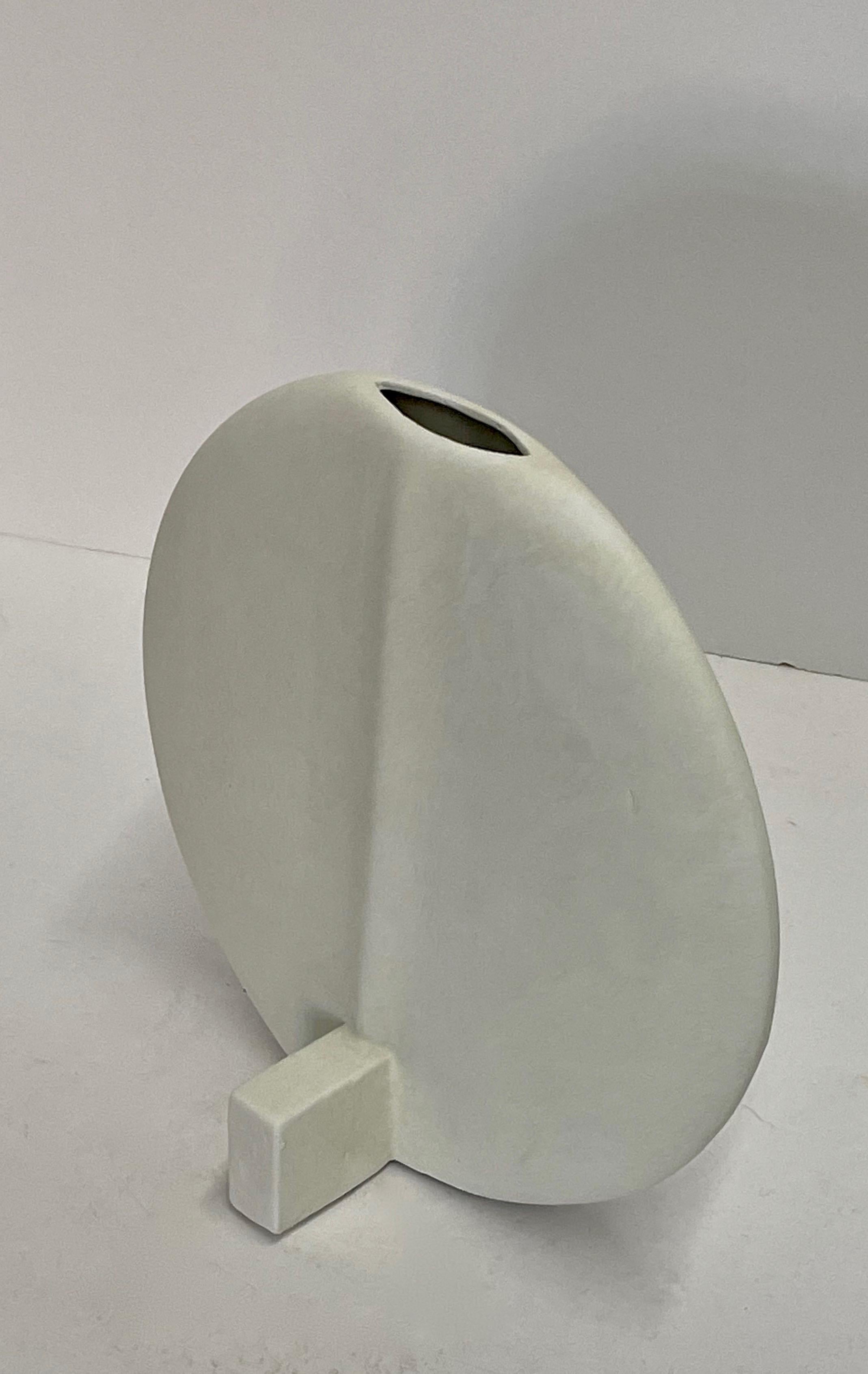 Contemporary Danish design mini sized thin disc shaped white glaze vase.
Center spout.
Sits on self stand.
Available in other sizes in dark grey.