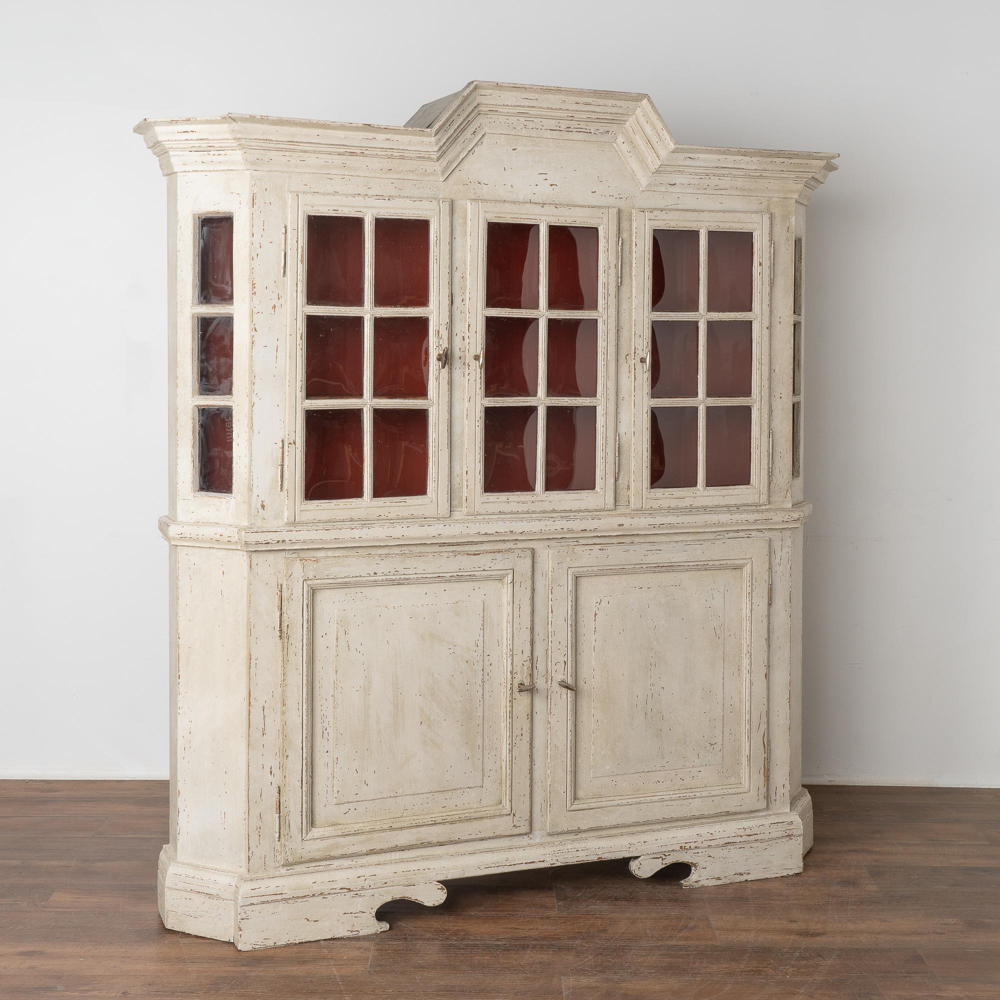 This Swedish country pine cupboard may be used as a display cabinet or bookcase. The upper pane glass doors allow for ideal display of any collection held within.
The newer professionally applied white painted finish is complimented by the