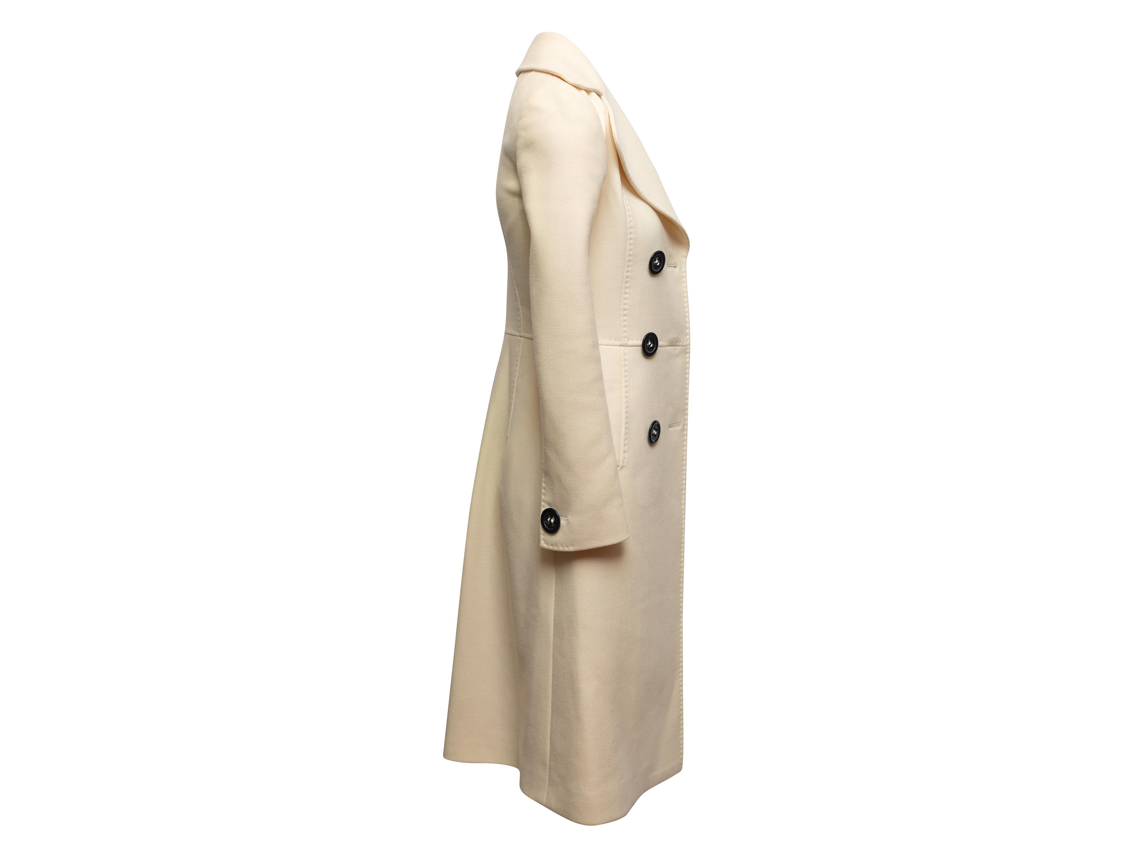 Cappotto lungo doppio petto in lana vergine bianca di Dolce & Gabbana. Risvolto dentellato. Doppie tasche sui fianchi. Chiusura frontale con bottoni. Busto 32