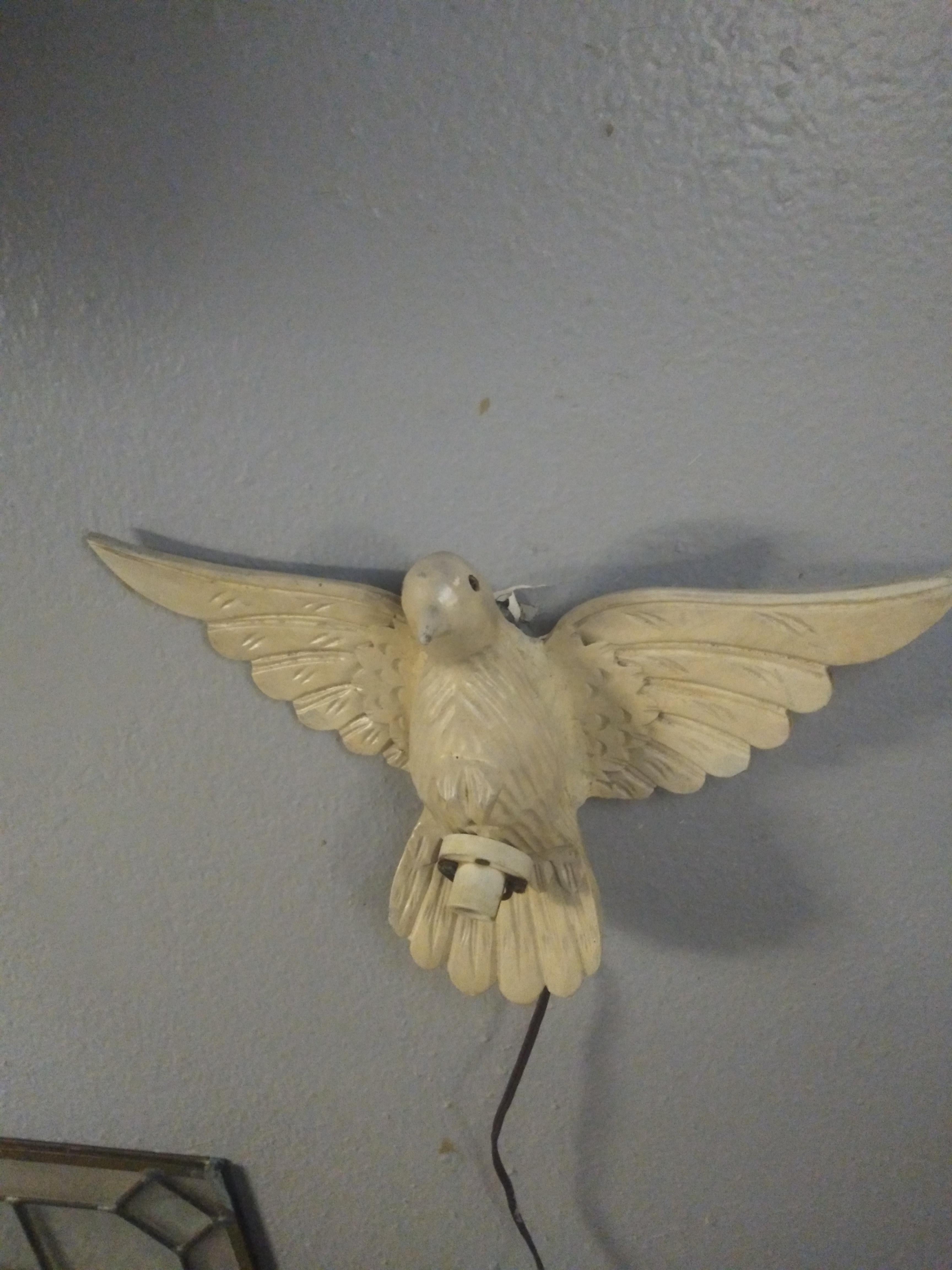 Il s'agit d'une colombe en bois sculptée et peinte à la main. Il s'agit d'un luminaire suspendu au mur, tout à fait original et inhabituel. Datant du début du 20e siècle.