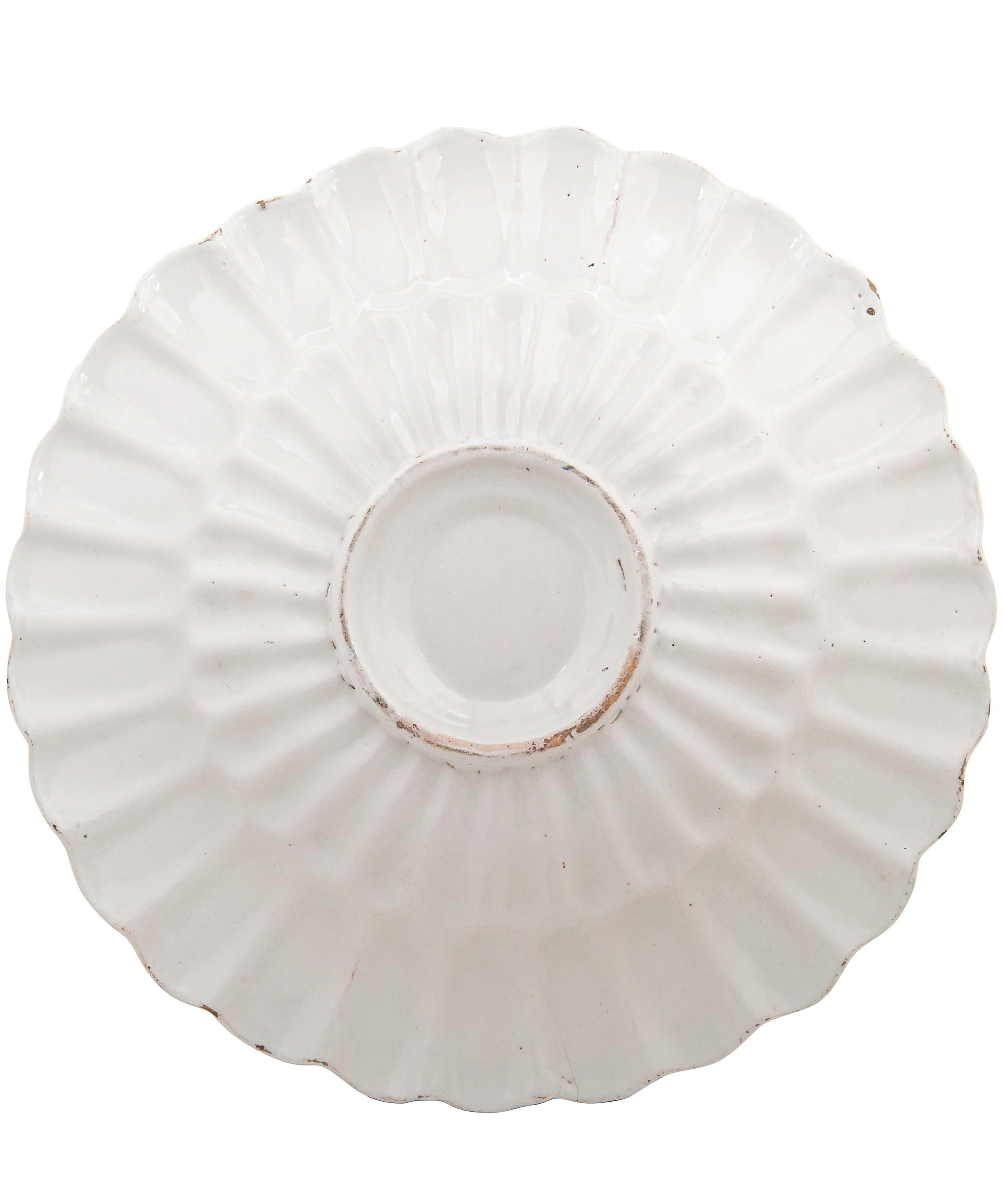 The edge of the dish consists of 29 lobes, which begin at the outer edge and disappear halfway into the shelf. The shelf of the dish is convex. The back is equipped with a stand ring.