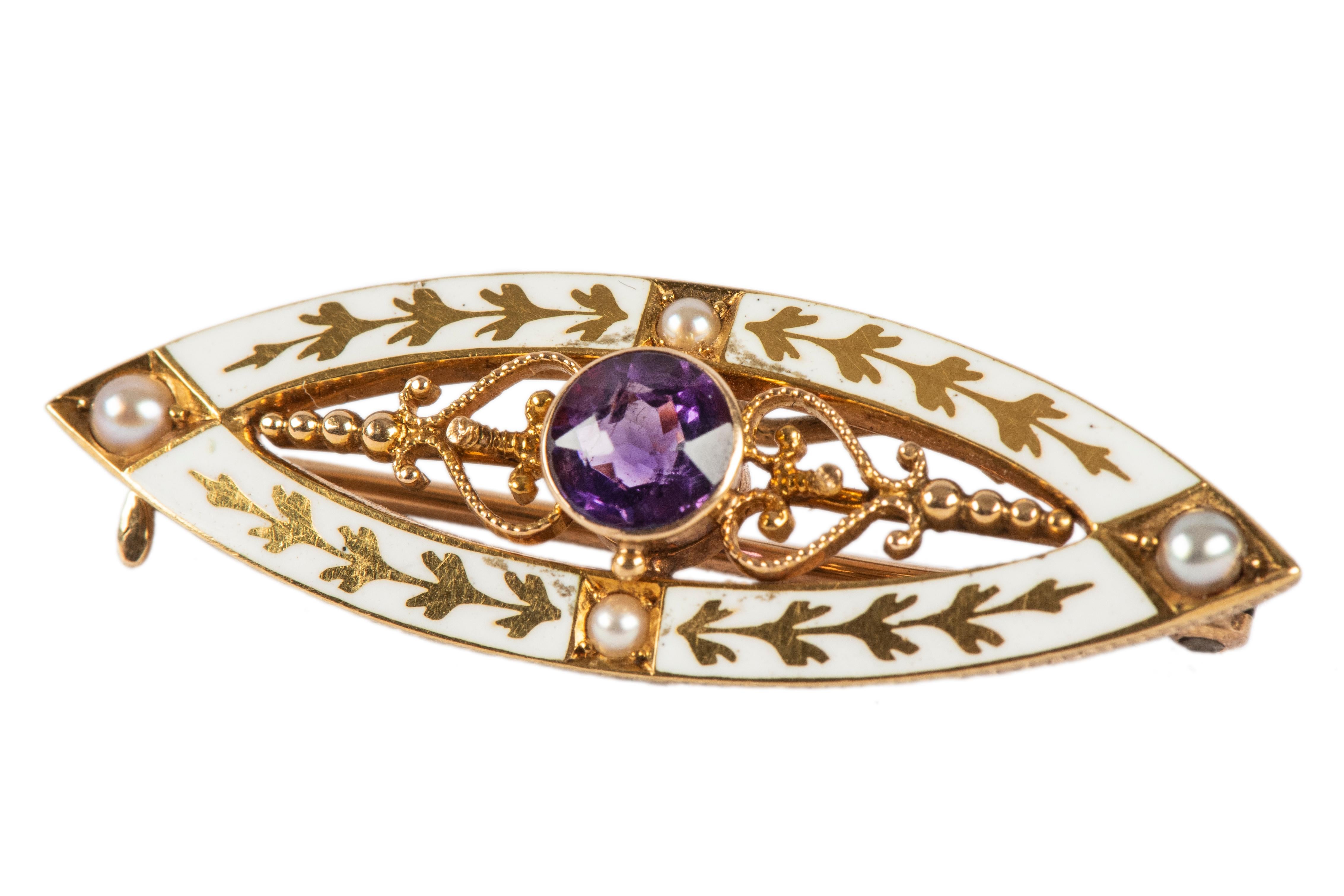 Of openwork elliptical design, with a white enamel border enhanced with gold laurel leaves and four small pearls. The centre features a bezel-set amethyst flanked by gold scrolls and beadwork. The early 20th-century American pin has added antique