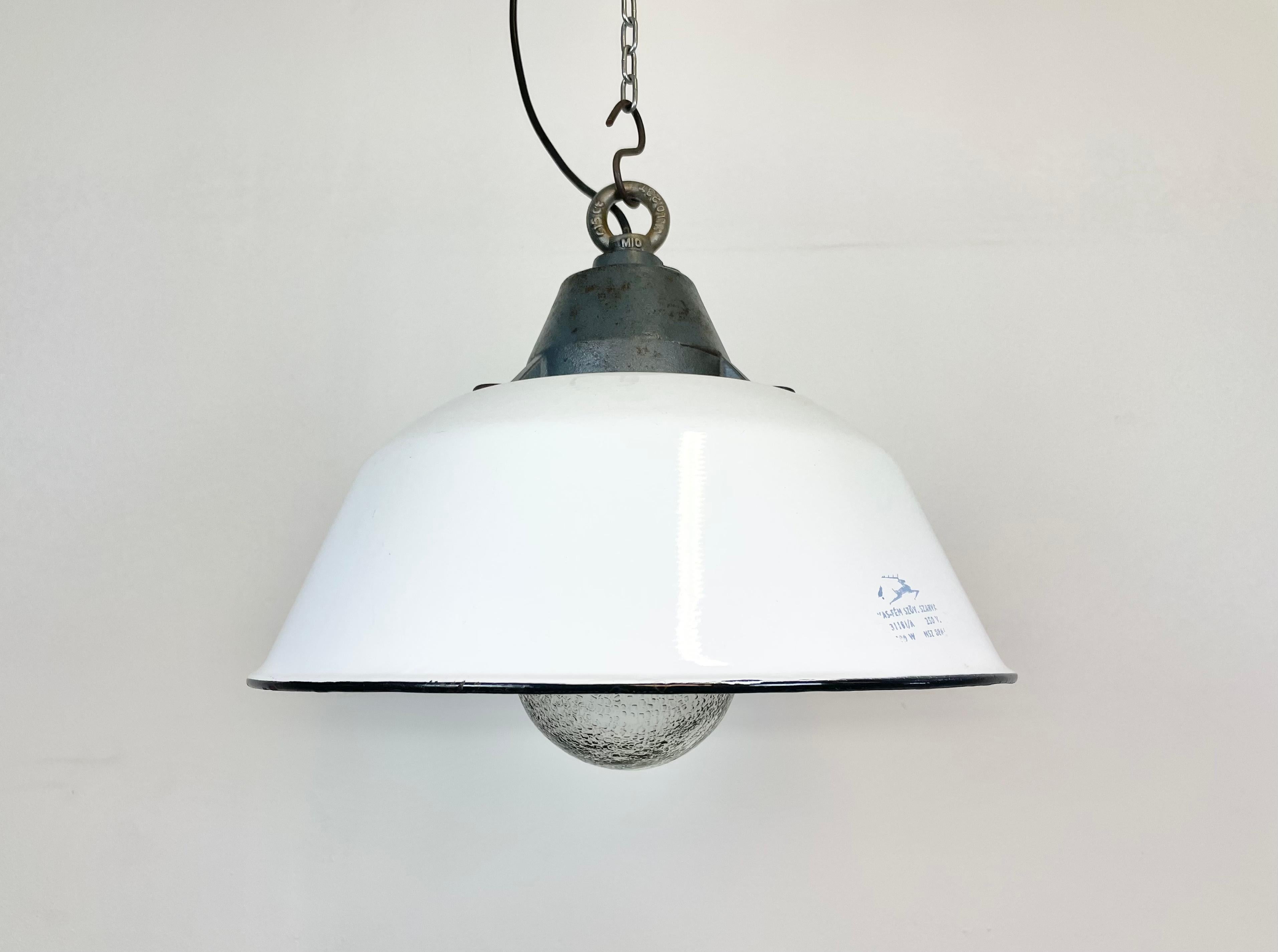 Industrial hanging lamp manufactured by Szarvasi Vas - Fém in Hungary during the 1960s. It features a white enamel shade, white enamel interior, a grey cast iron top and frosted glass cover New porcelain socket requires E 27 light bulbs. New wire.