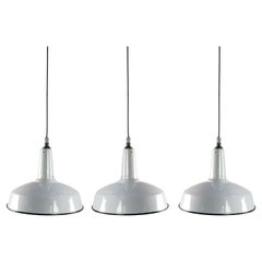 Ensemble de trois lampes suspendues industrielles en fonte et émail blanc