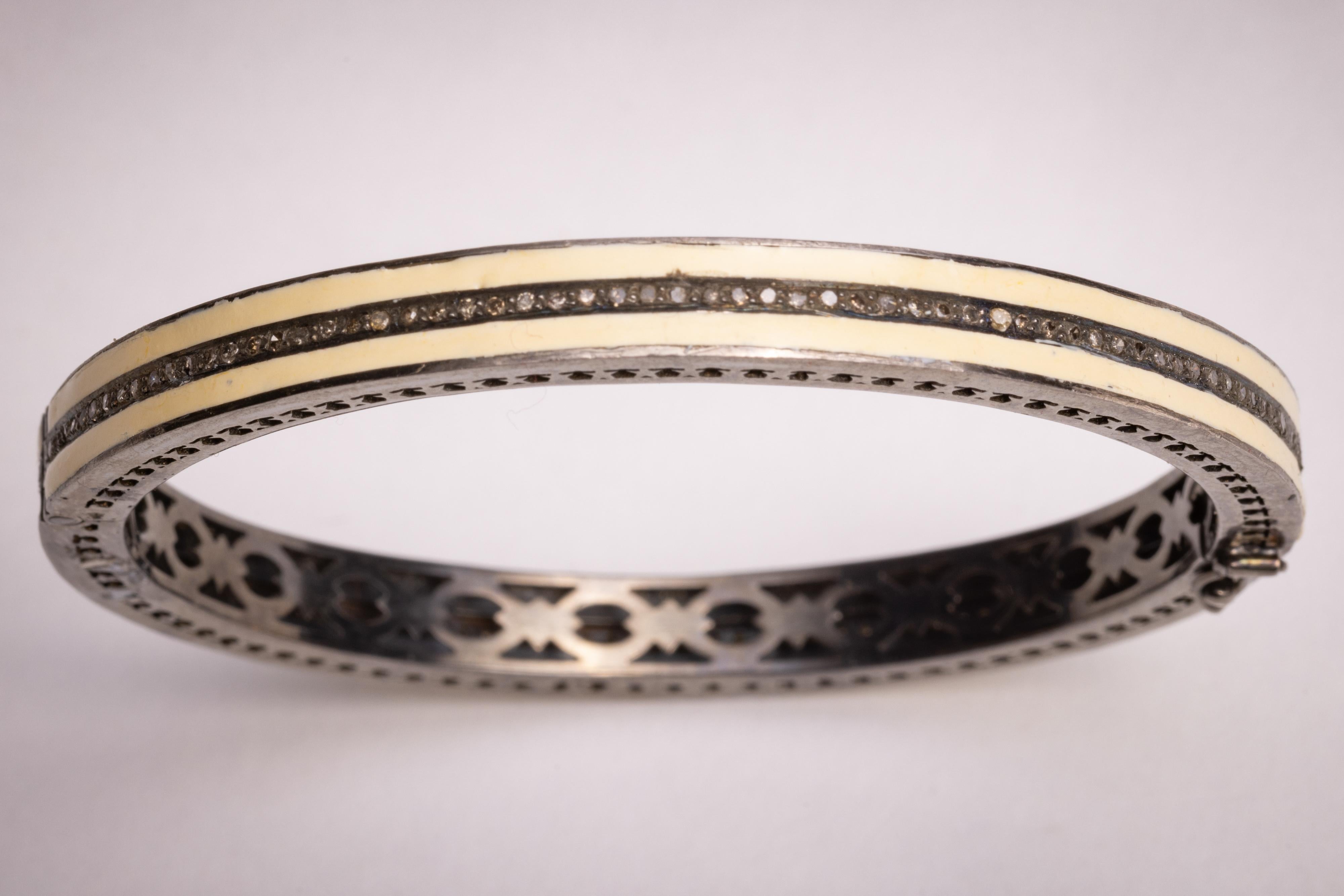 A white enamel and sterling silver bangle bracelet with a line of round, brilliant cut diamonds set down the middle.  Inside circumference is 7