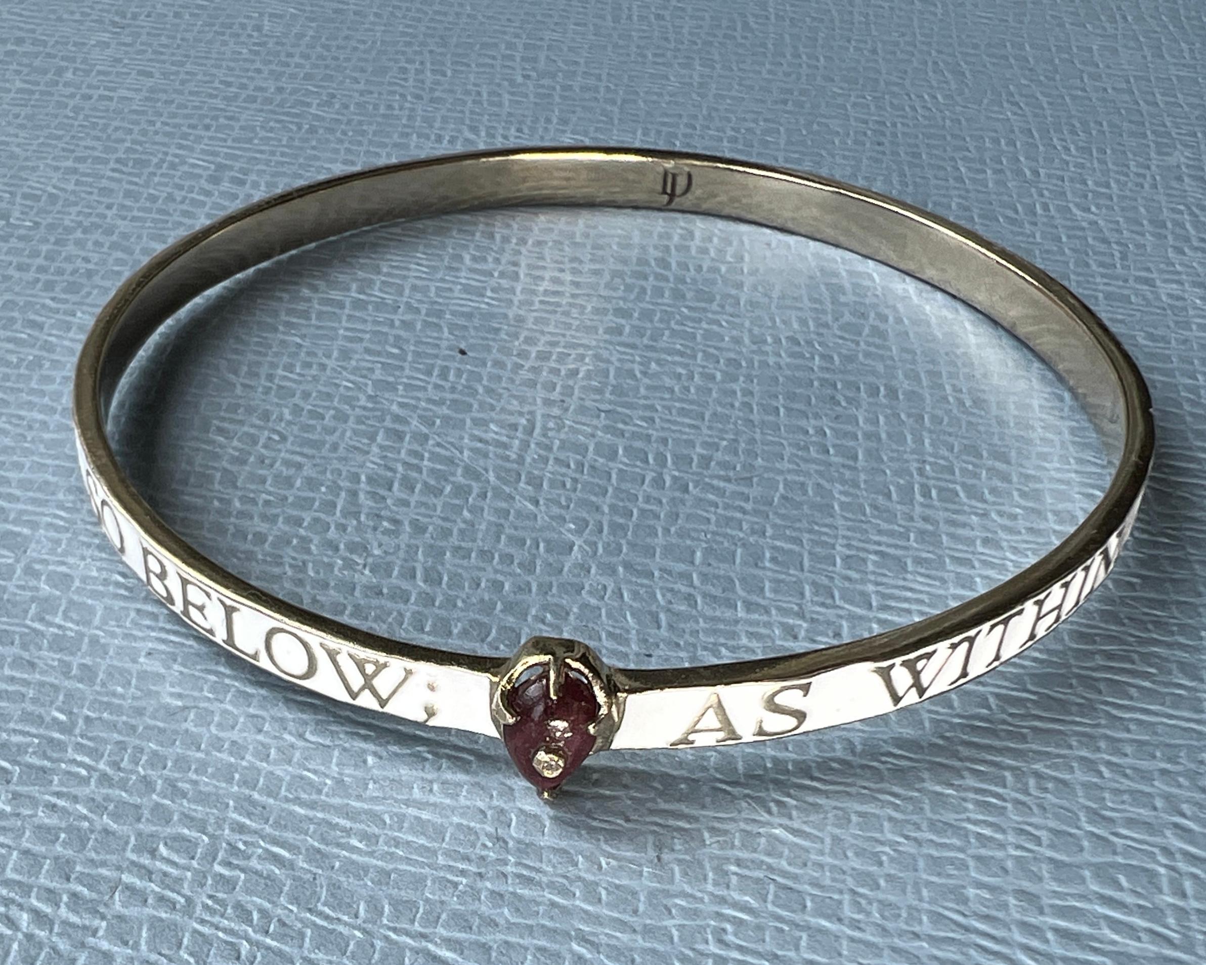 White Enamel Bangle Bracelet Diamond Garnet Heart 

Inspired by Hermetica and Kabbalistic concepts of the micro and macro cosmos. With the inscription As above so below, As within so without.

Material: 14 Gold plated Brass with white enamel
Gem: