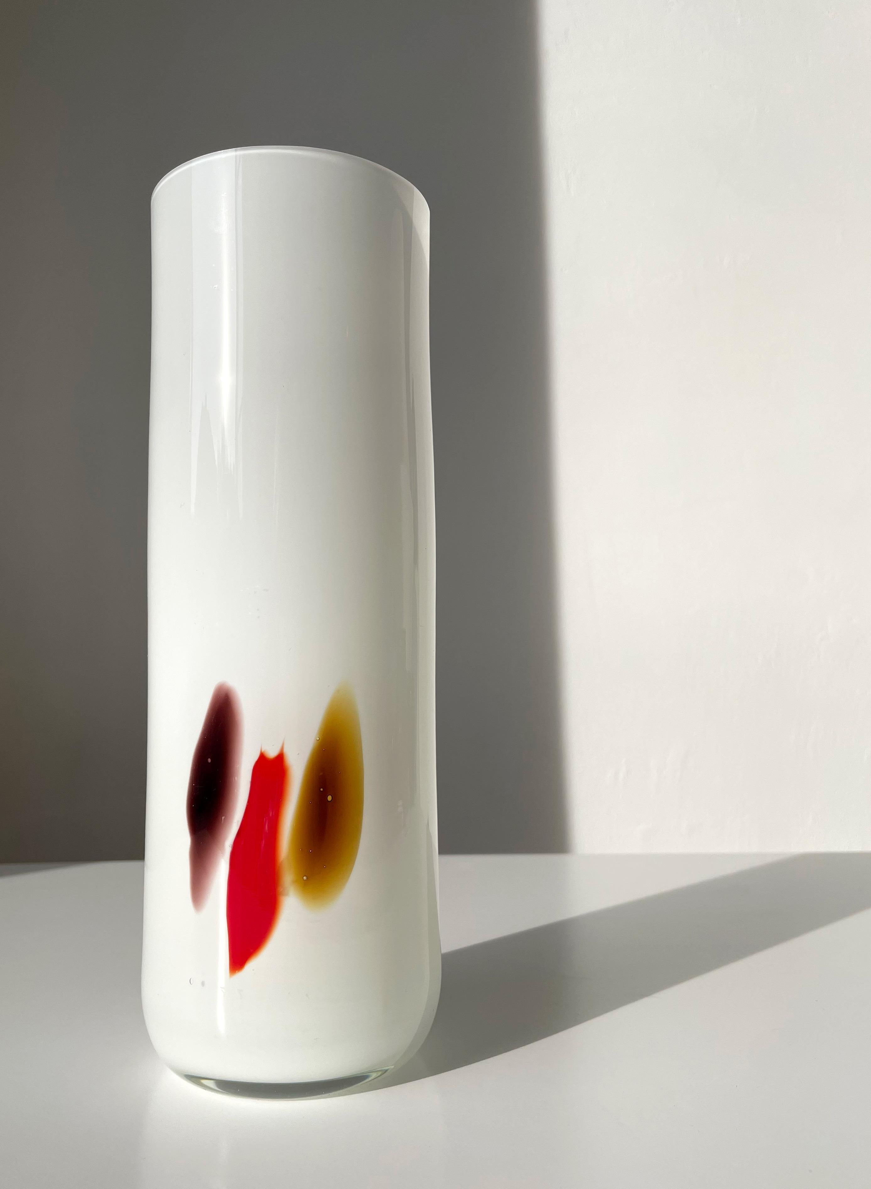 Tall milky white cased in clear glass cylinder shaped Danish modernist art glass vase with three organic decorations in plum, blood red and umber colors. Manufactured in the town of Naestved by Holmegaard in the 1970s. Beautiful vintage