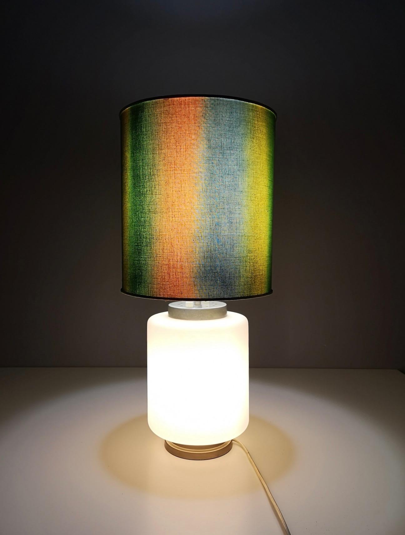 Made in Italy, anni '60.
È realizzato in vetro, metallo e tessuto. 
Questa lampada da tavolo è dotata di due luci: possono essere accese separatamente o contemporaneamente. 
Potrebbe presentare lievi tracce d'uso in quanto vintage, ma può essere