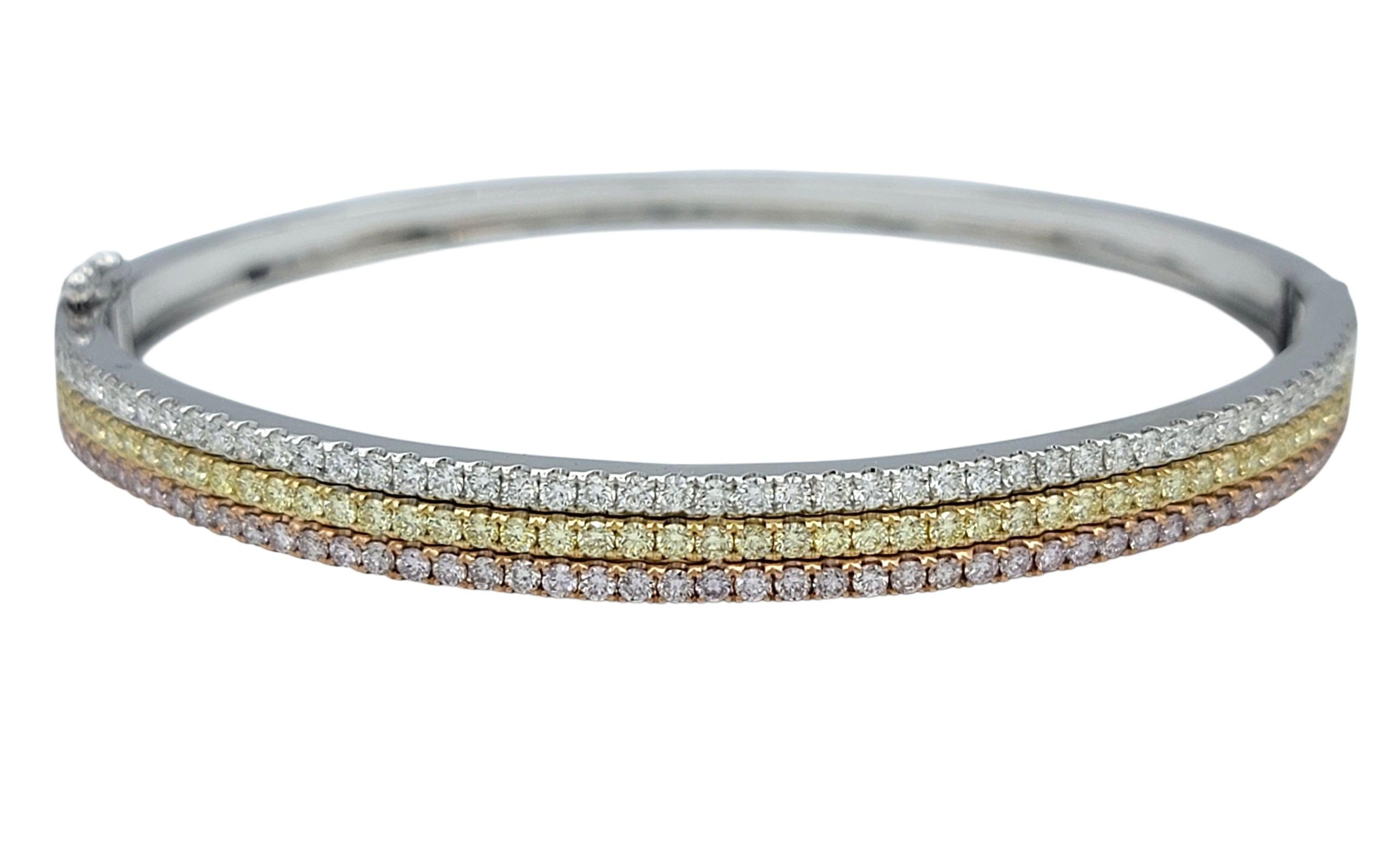 Dieser raffinierte Armreif glänzt mit einem Trio aus farbigen Armbändern.  Diamanten - mit eleganten Reihen von hellrosa, hellgelben und klassisch weißen runden Brillanten. Die Palette ist anmutig in einem schlanken, gestapelten Design angeordnet,