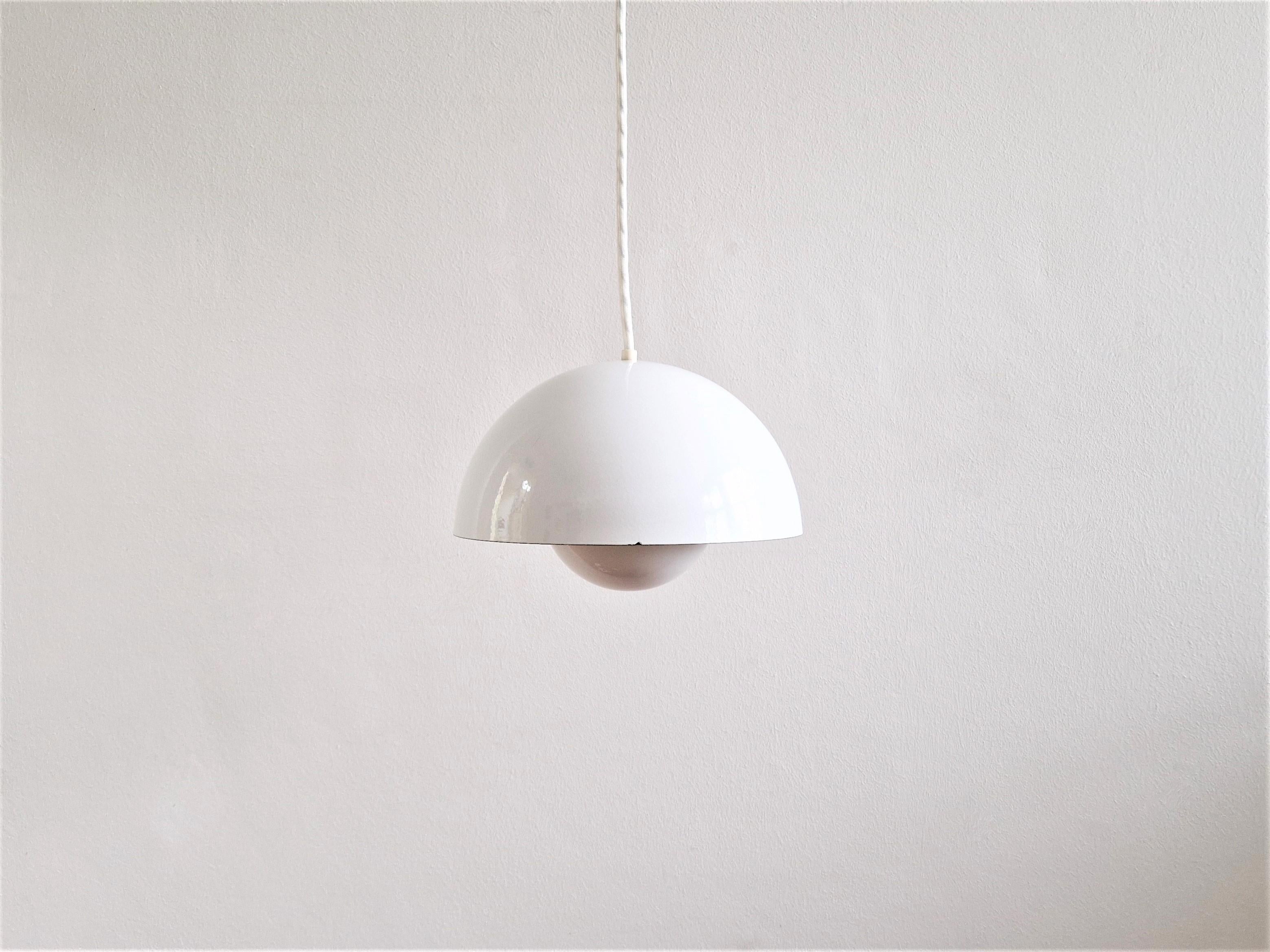 The Flowerpot pendant lamp was designed by Verner Panton for Louis Poulsen in 1968. These lights are likely to be produced in the 1980's. This piece has a white enameled finish outside and inside. The smaller reflector shade has an orange enamel