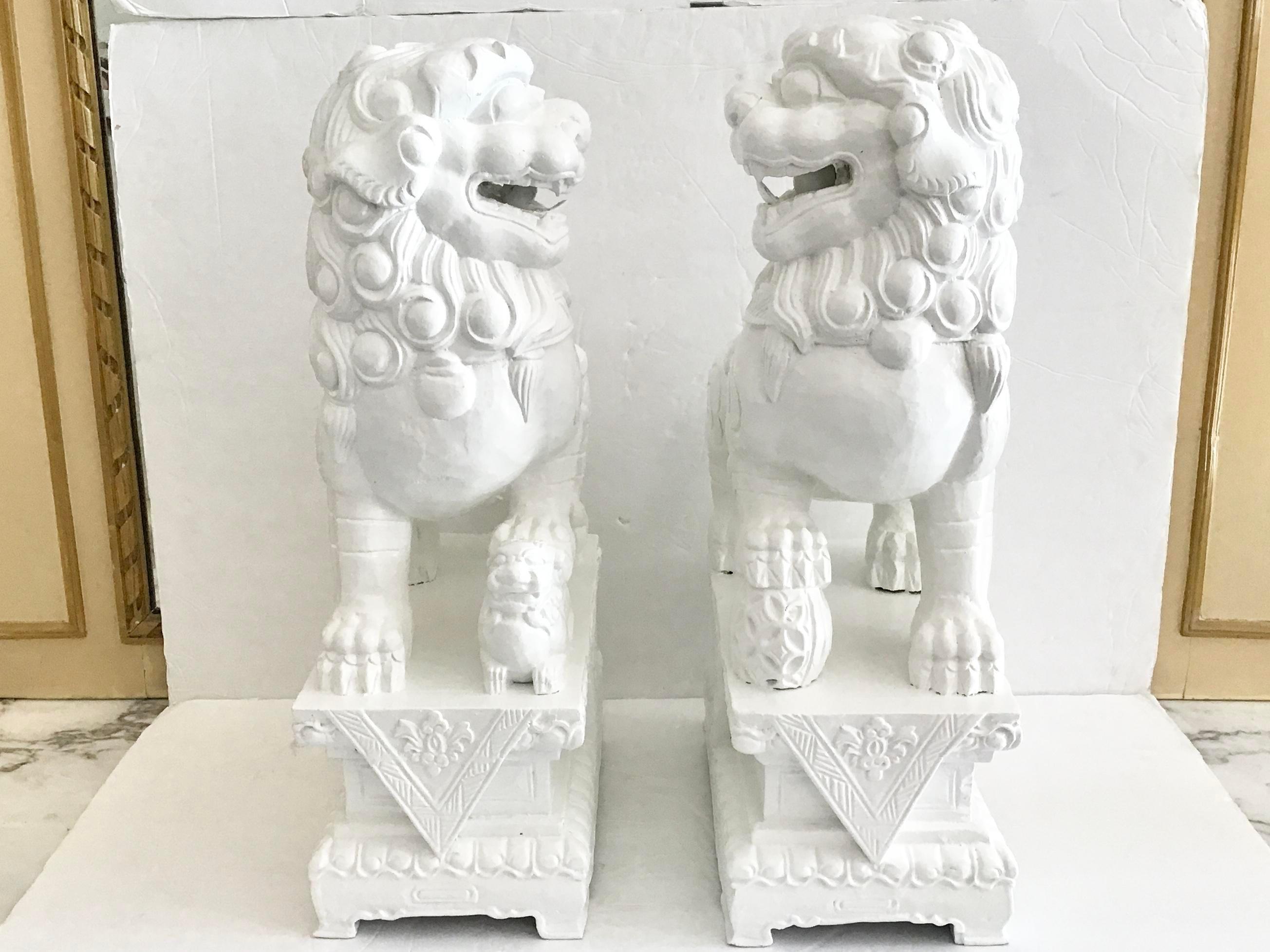 Pair of freshly lacquered in white fantastic large foo dogs made of wood. The floral carving details at the base is amazing. Add it to your collection of Asian art.