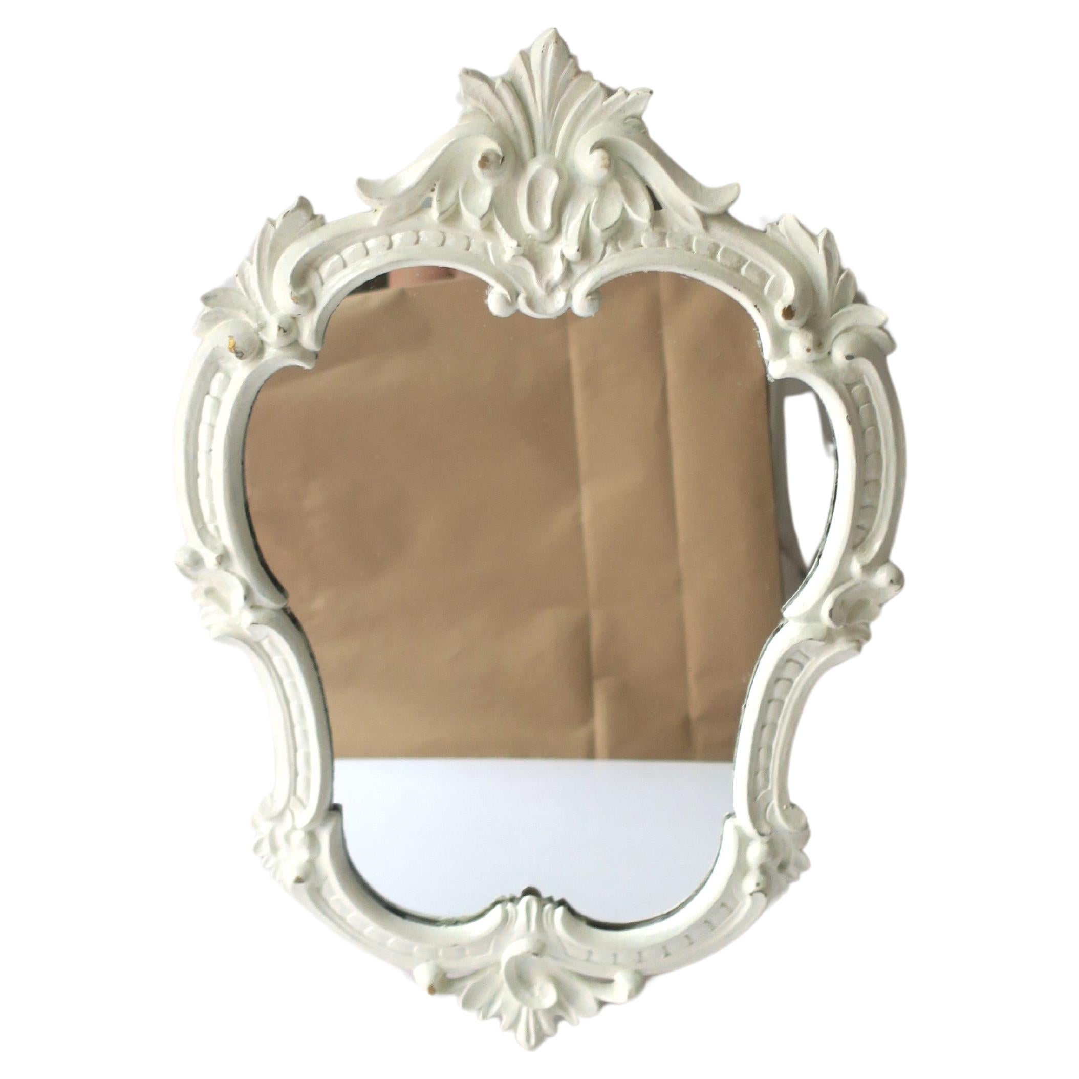 Miroir mural vintage encadré de blanc, dans le style Rococo, vers le milieu du 20e siècle. Le miroir est en bois, peint en blanc, et est préparé pour être suspendu au dos comme indiqué sur la dernière image. La pièce est d'une taille pratique et