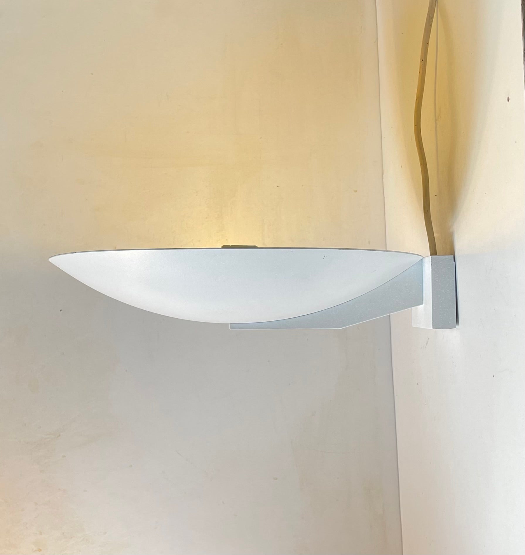 Un'applique fissa progettata e prodotta da Pierre Disderot Paris negli anni '80. Si tratta di un'applique che proietta la luce verso il soffitto creando un'illuminazione ambientale e accogliente nella stanza. Può essere facilmente utilizzata anche