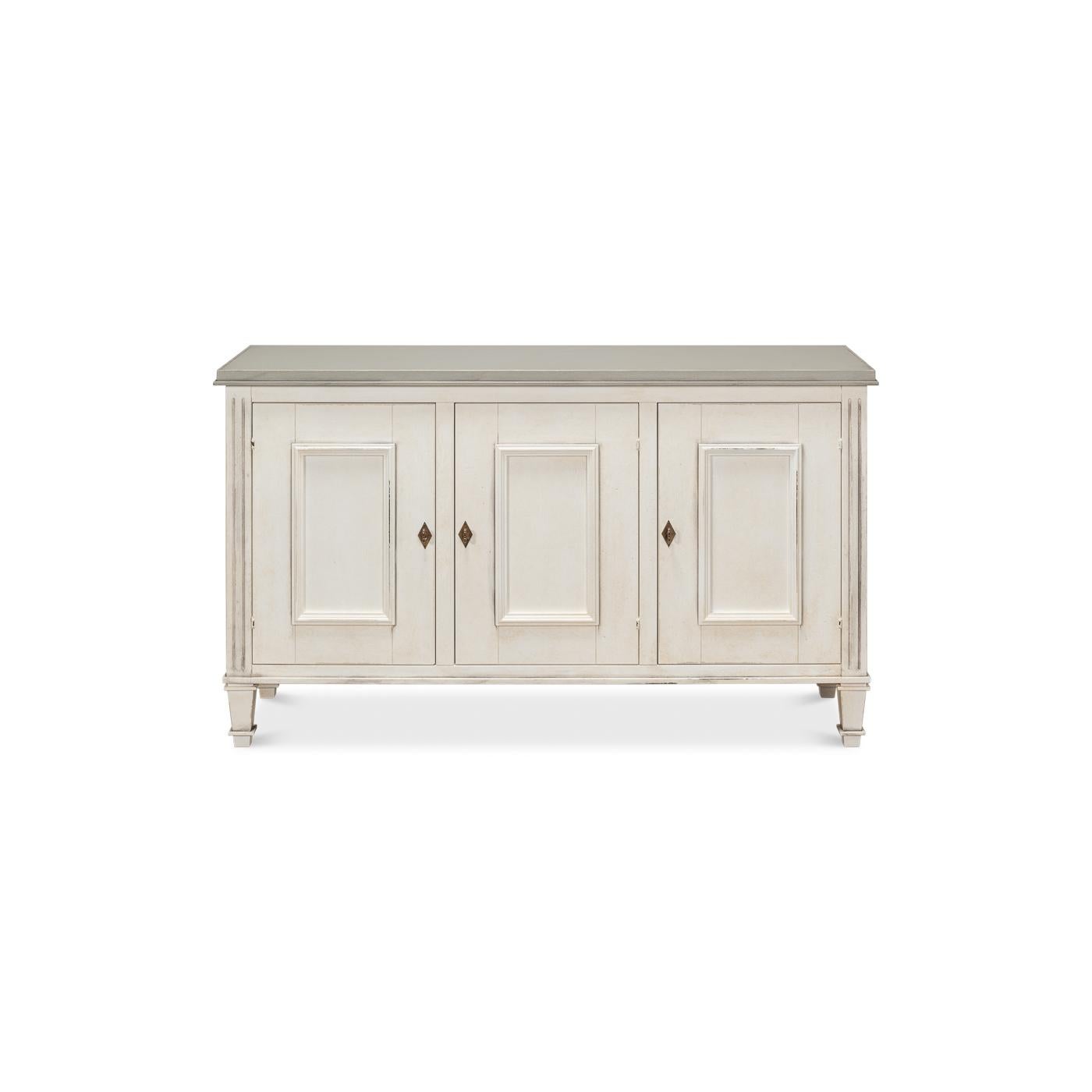 Ispirato allo stile provinciale neoclassico della Francia del XVIII secolo, questo squisito pezzo vanta una finitura bianca anticata con un piano grigio. Il design simmetrico è caratterizzato da tre porte a pannelli, ognuna delle quali è ornata da