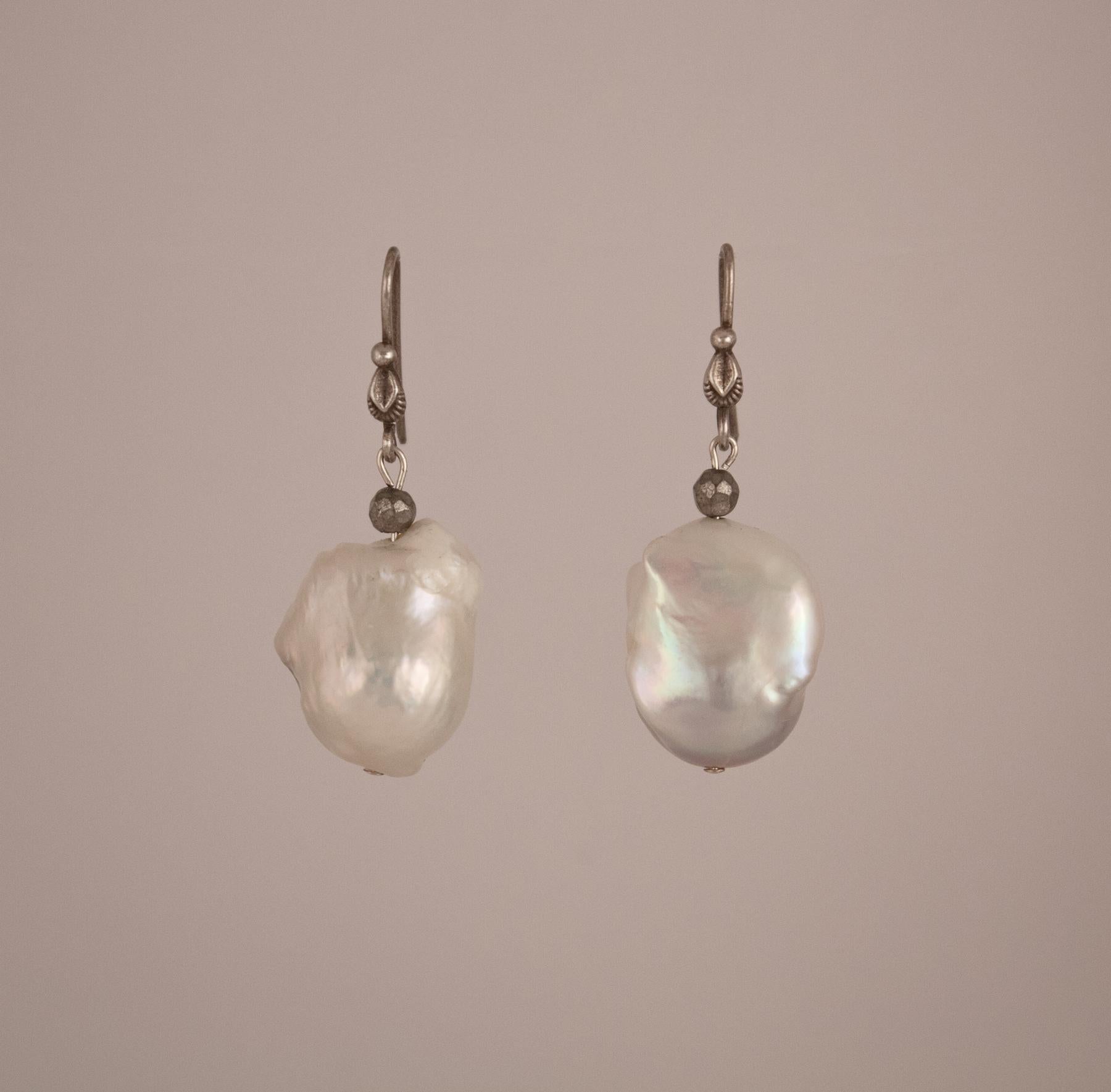 A lovely pair of white baroque pearl dangle earrings on sterling silver wires. The well-matched pearls, which are a wearable size, have beautiful color and luster. The silver findings lend a more casual air to the pair.   