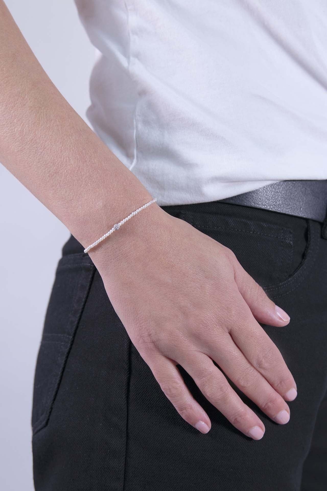 This bracelet is made of delicate white mini freshwater pearls with a 2mm diameter, embodying purity and elegance.  
There is a White Gold Diamond Pavé Bead in its center: The bead is made of 14k white gold, adorned with 21 white diamonds all