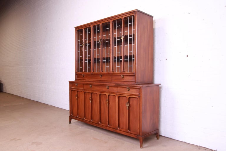 An exceptional Mid-Century Modern breakfront bookcase cabinet or sideboard with hutch top

By White Furniture

USA, 1960s

Sculpted walnut, with leaded glass doors and original brass hardware.

Measures: 66.75