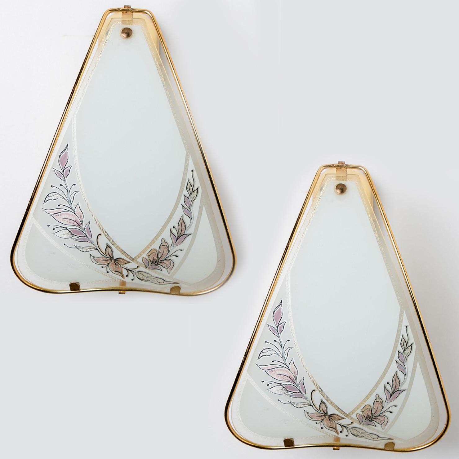 Pair of high-end wall sconces from Sweden. Each wall fixture features a brass base with an opaque white glass element.
The glass is decorated with a pink and purple flower pattern.

Please note the price is for the pair.

Dimensions:
Height: 11.81