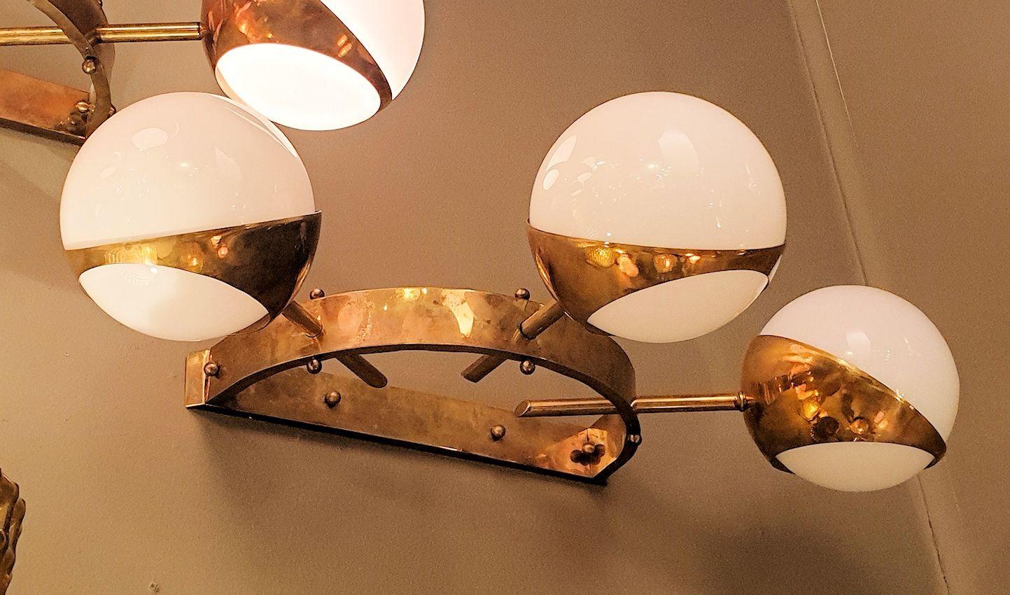 Mid-Century Modern large wall sconces, attributed to Stilnovo, Italy, 1960s.
The pair of large sconces is made of white translucent glass globes and cast brass mounts.
The vintage sconces have 3 lights each, nested inside the three glass