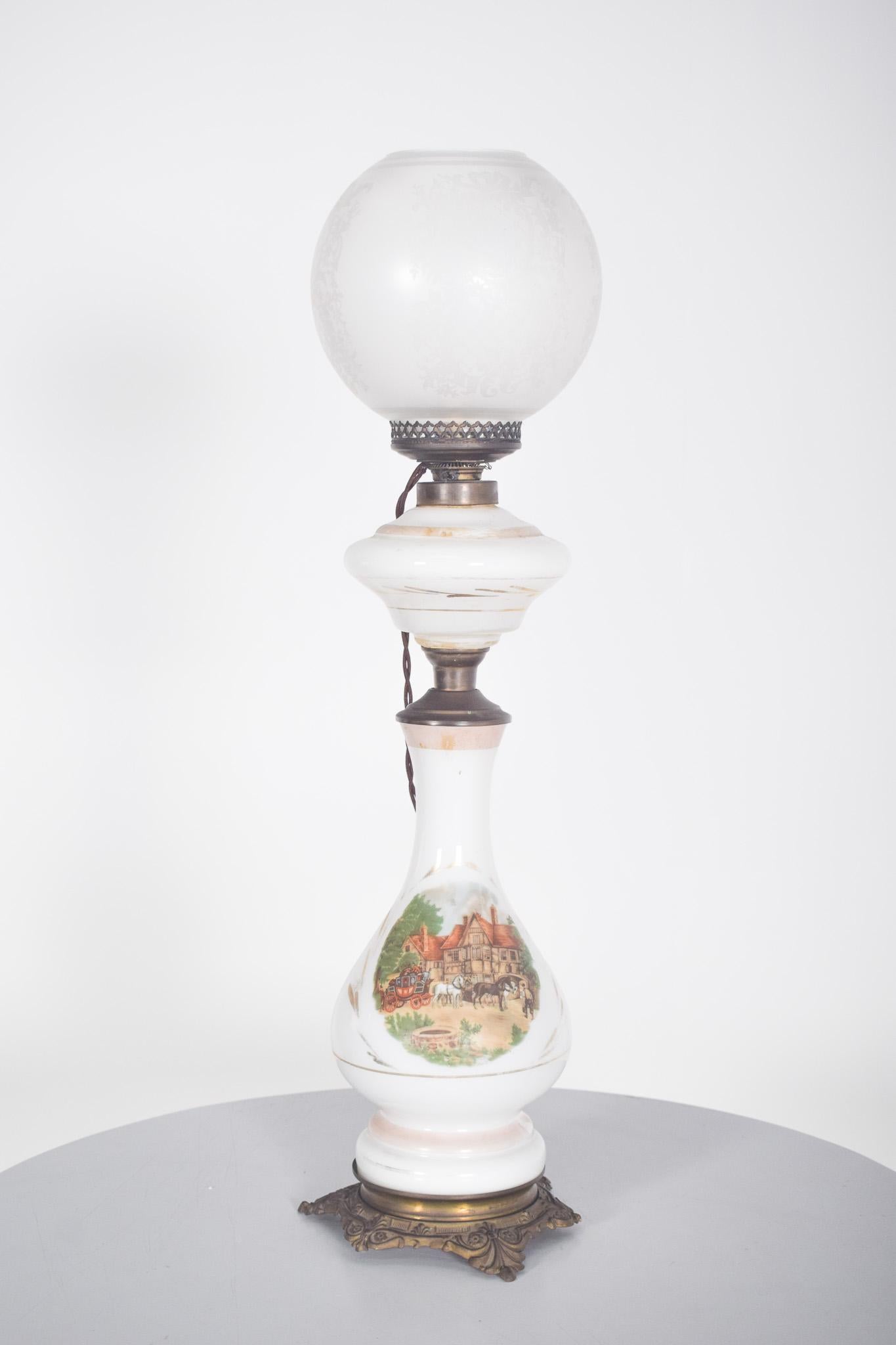 Lampe aus weißem Glas und Metall, mit zwei Körpern. Auf einem bearbeiteten Metallsockel folgt der Hauptkörper aus Milchglas in einer länglichen und zarten Silhouette, die mit einer schönen handgemalten ländlichen Szene verziert ist, die ein